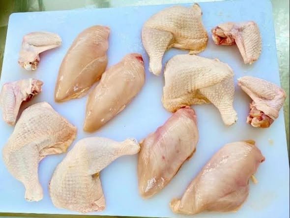 chicken breasts and legs on a white cutting board