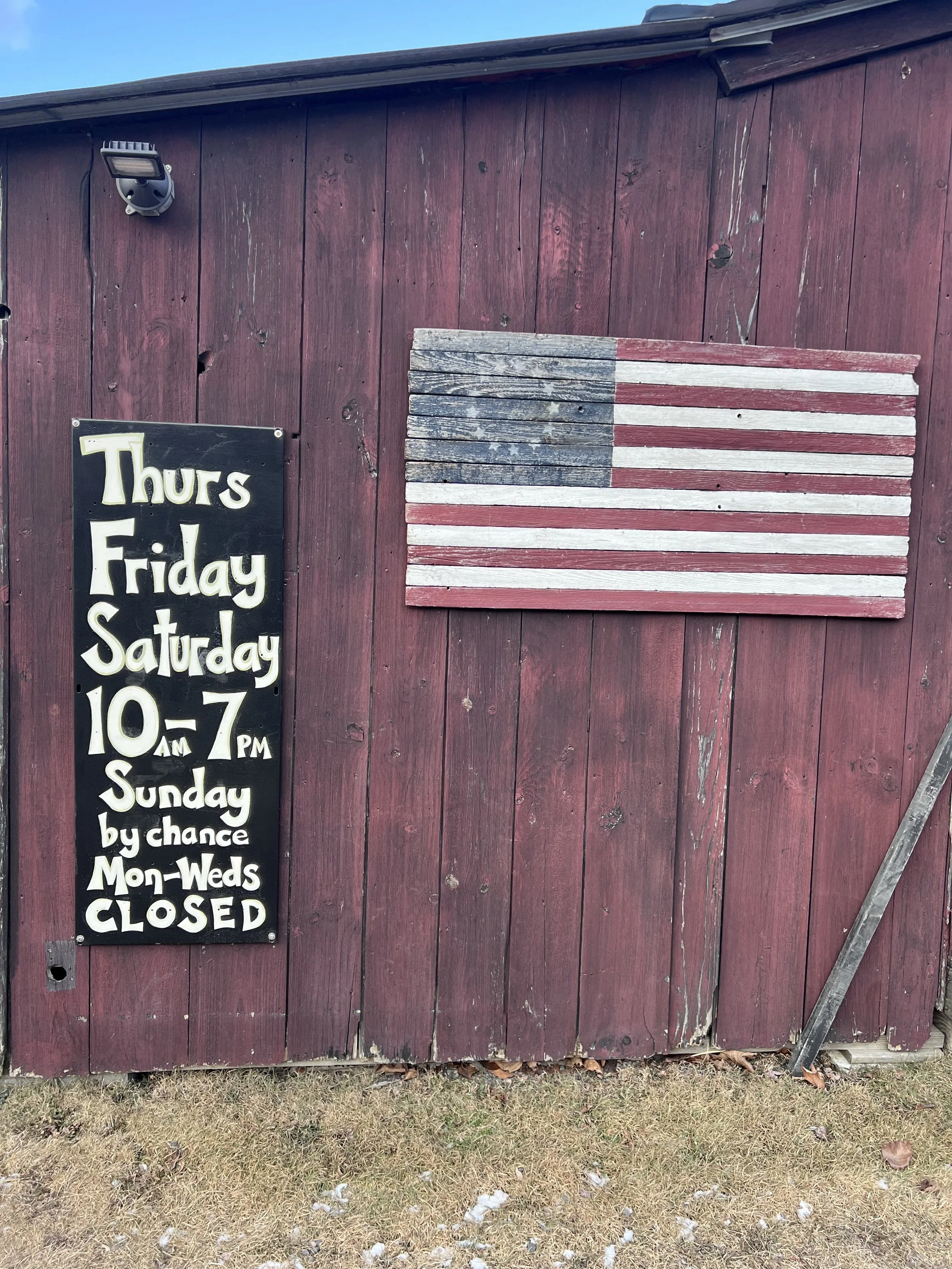 photo of the outside of the barn, with the days and hours listed on a black board