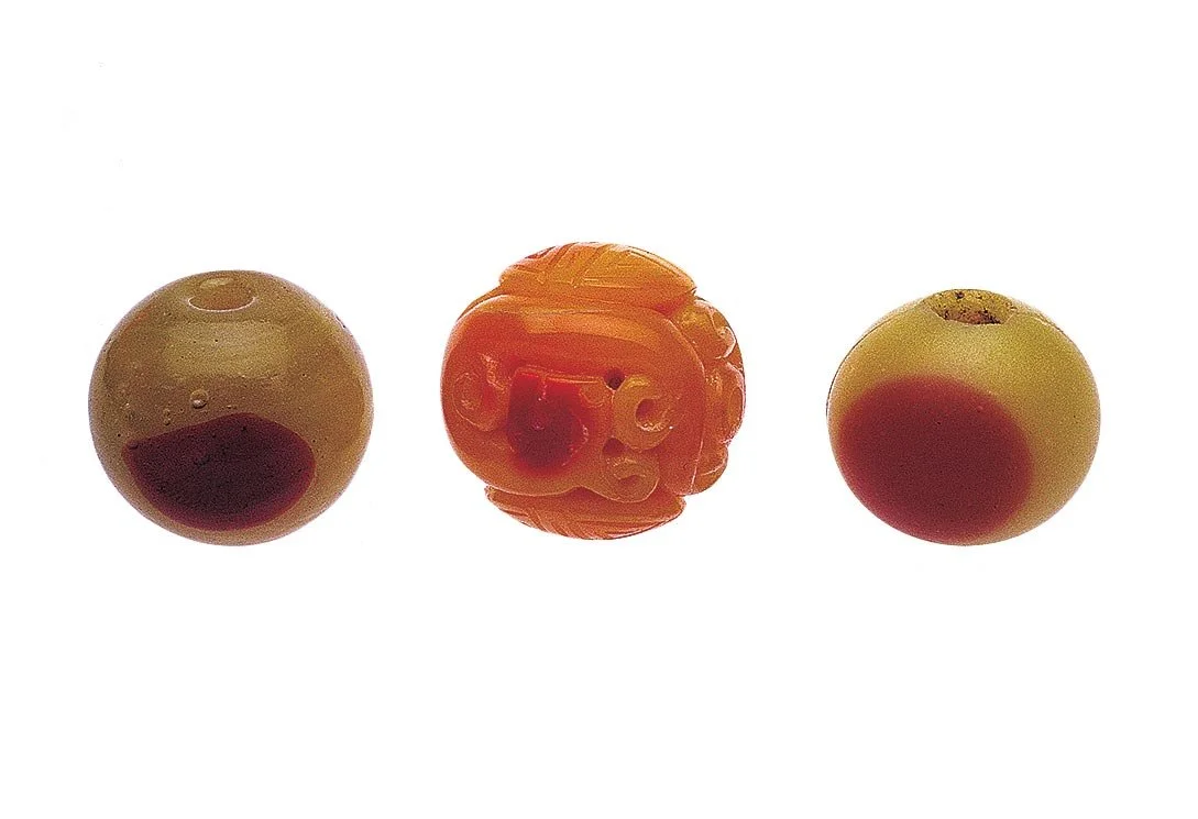 REAL AND GLASS SIMULATIONS OF HORNBILL BEADS USED AS OJIME: precious materials were often copied and used as ojime—actual hornbill bead has been damaged by insects eating into the casque of the keratin protein used for making this ojime. The image b