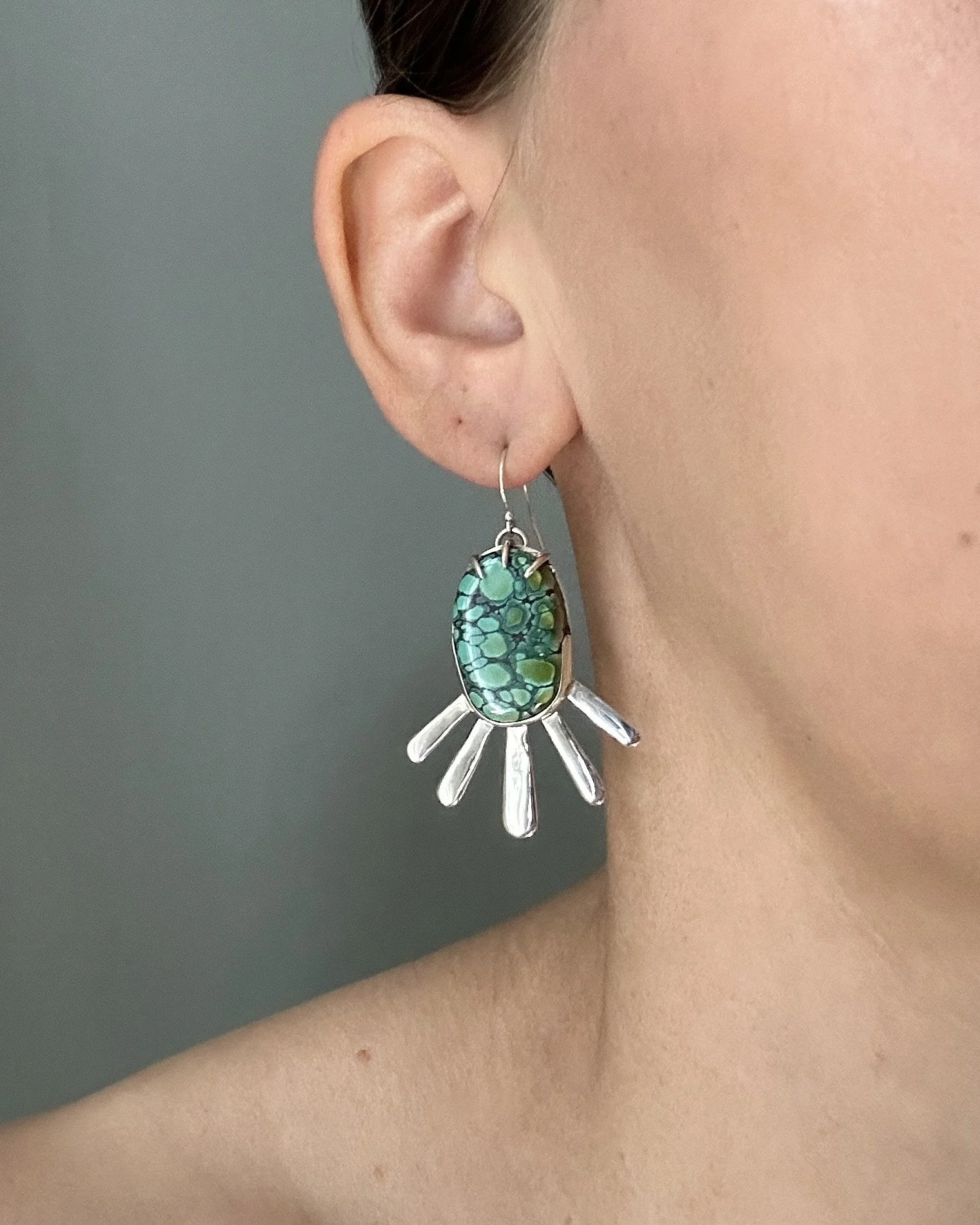 Hubei turquoise sun ray drop earrings, modeled by the jewelry artist