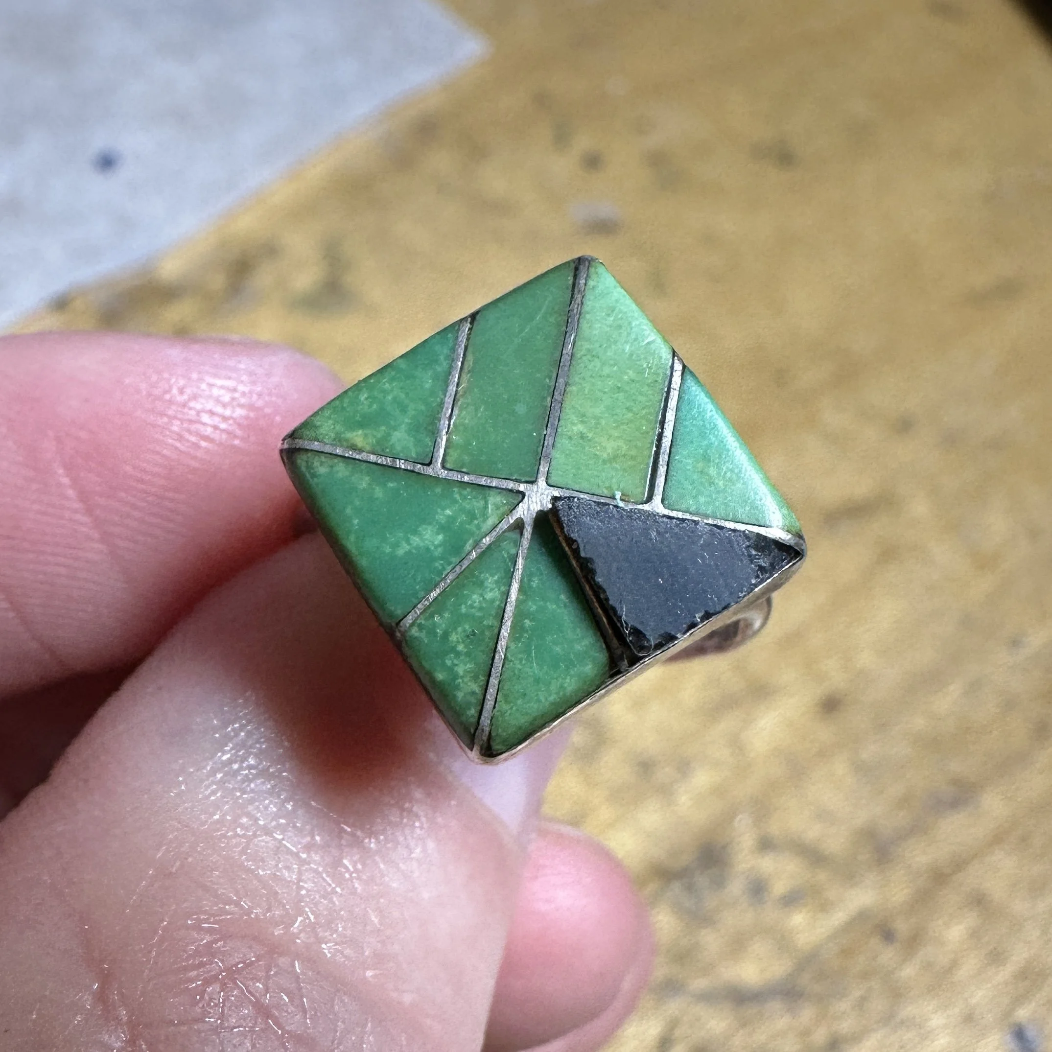 In the middle of an inlay ring repair where you can se the new piece of onyx cut and fit in the triangular section.