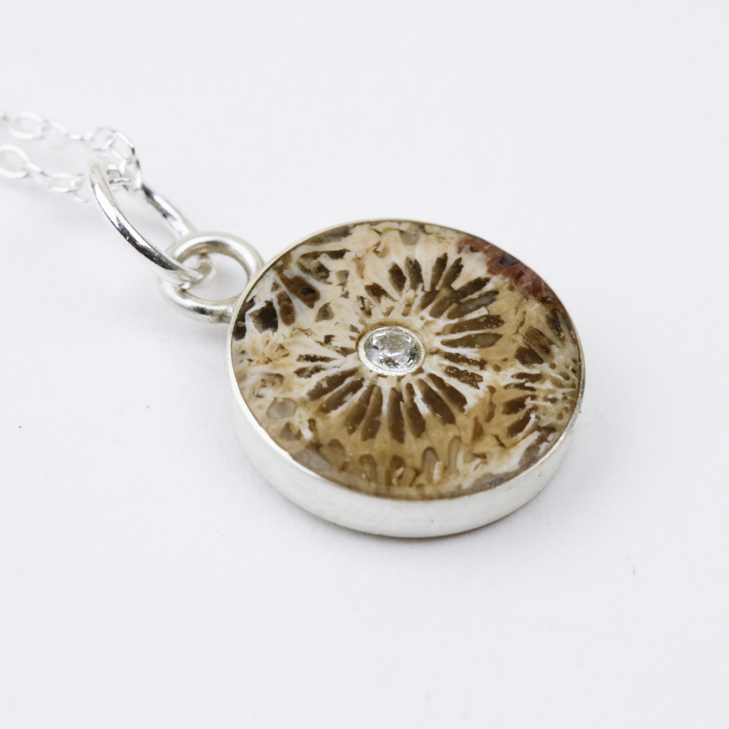 Agatized coral pendant isolating a polyp bloom, inset with a cubic zirconia