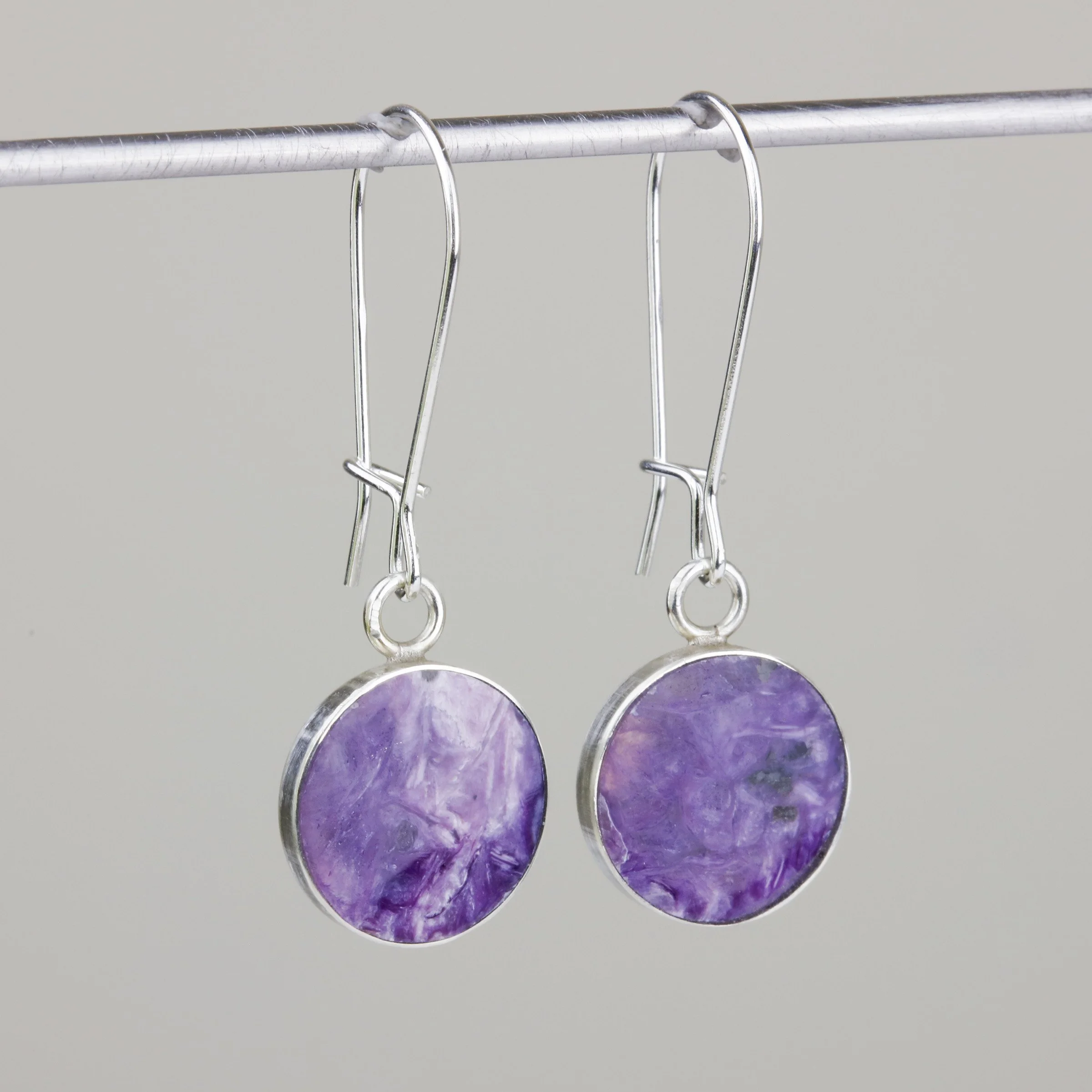 Small drop earrings inlaid with purple charoite natural stone, showing how fragile stones are better for certain types of jewelry than others