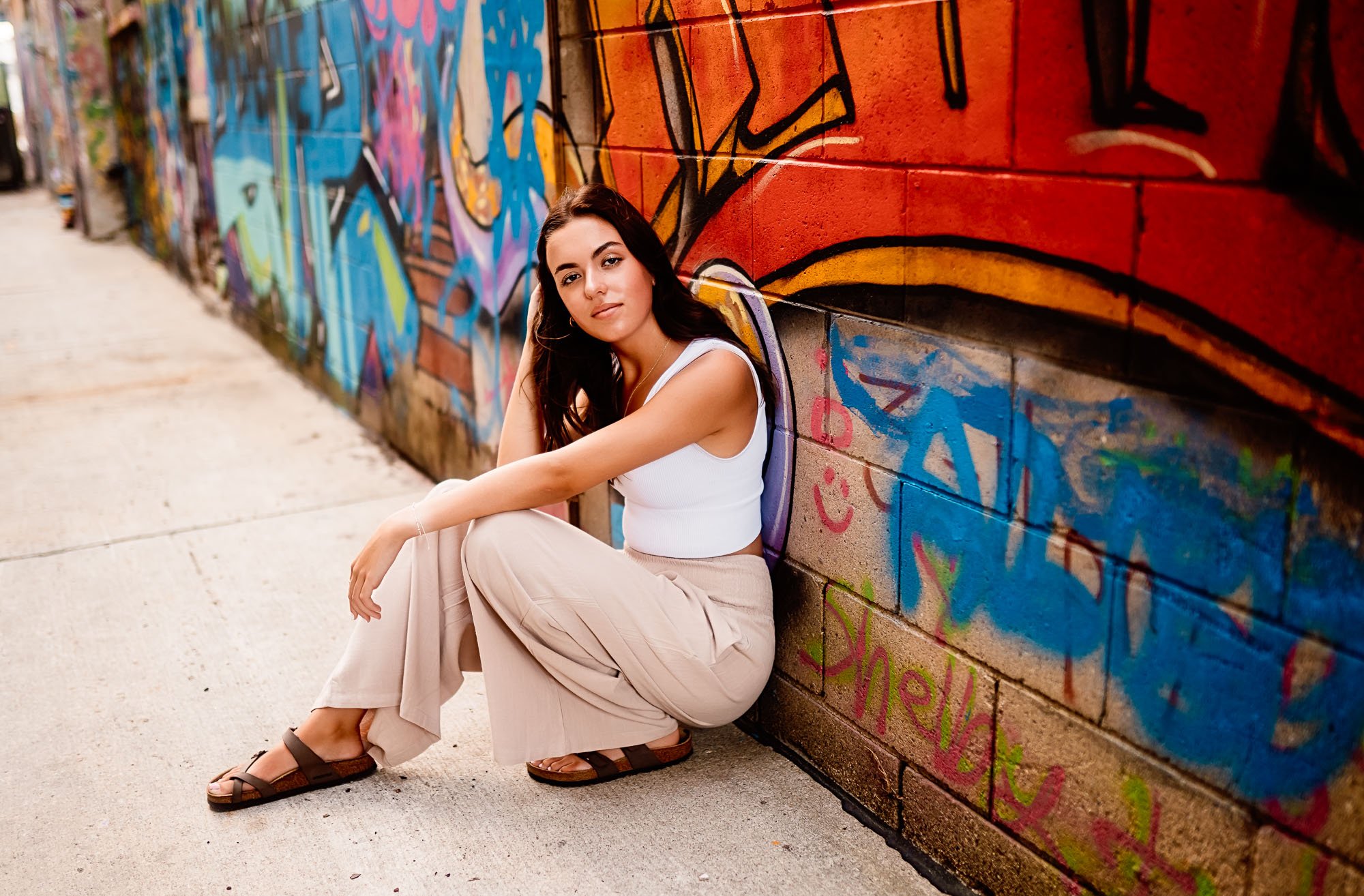 High school senior girl posing next to a colorful graffiti wall downtown Rochester, MN