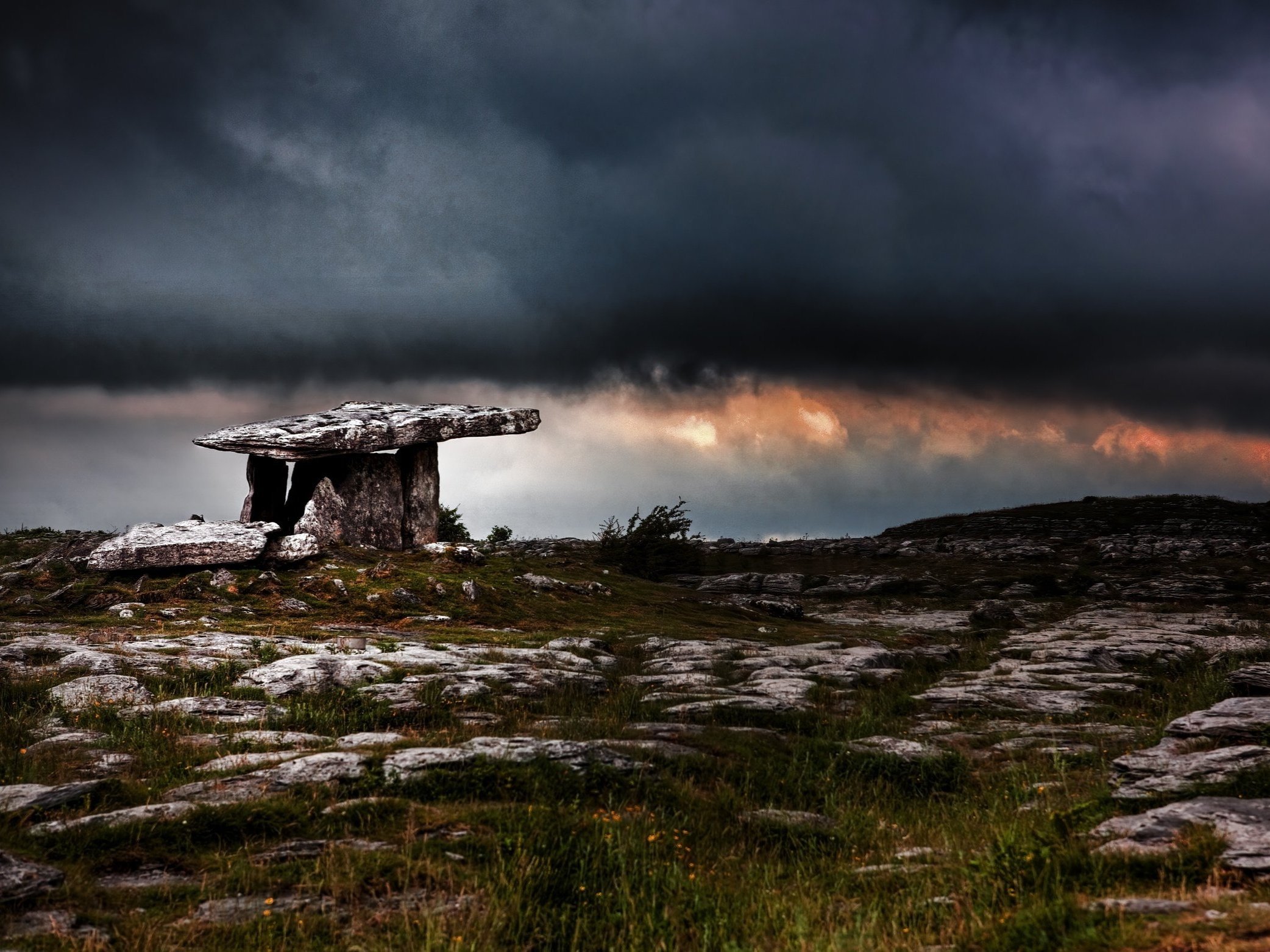Poulnabrone Dolmen in the Burren, County Clare, beneath stormy skies — an ancient portal tomb steeped in Irish myth.