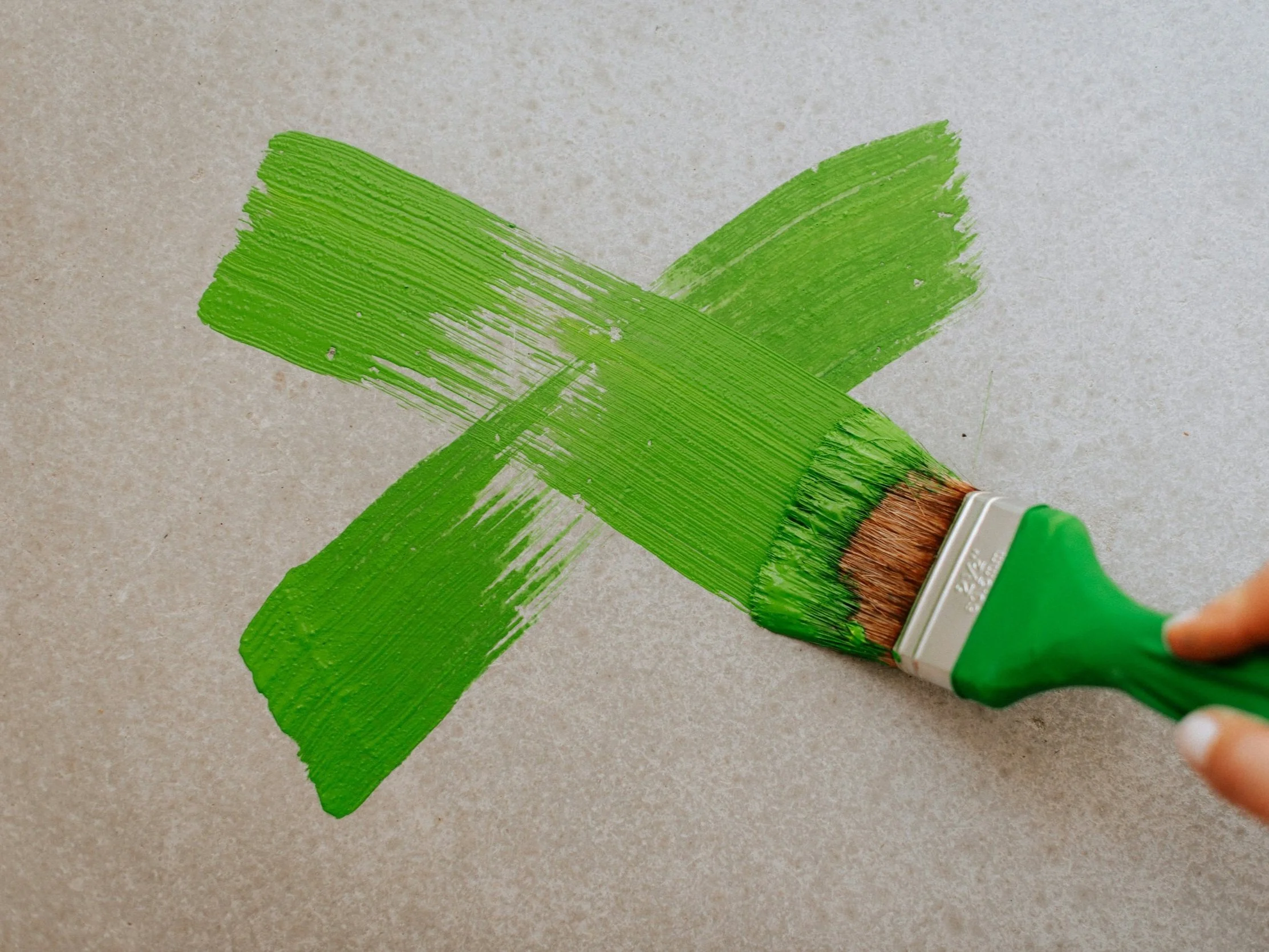 Green X painted with brush to represent rejecting greenwashing and making authentic sustainable choices.
