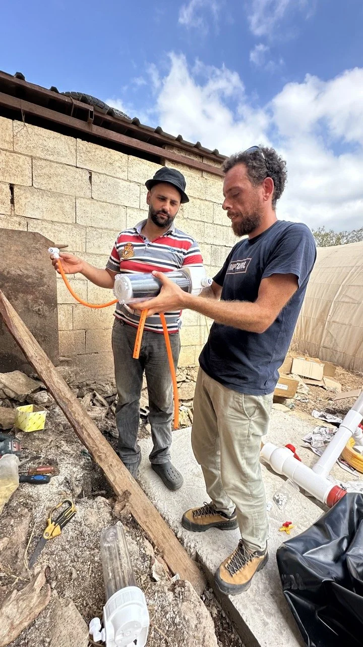 Person shoveling compost on a farm with greenery in background