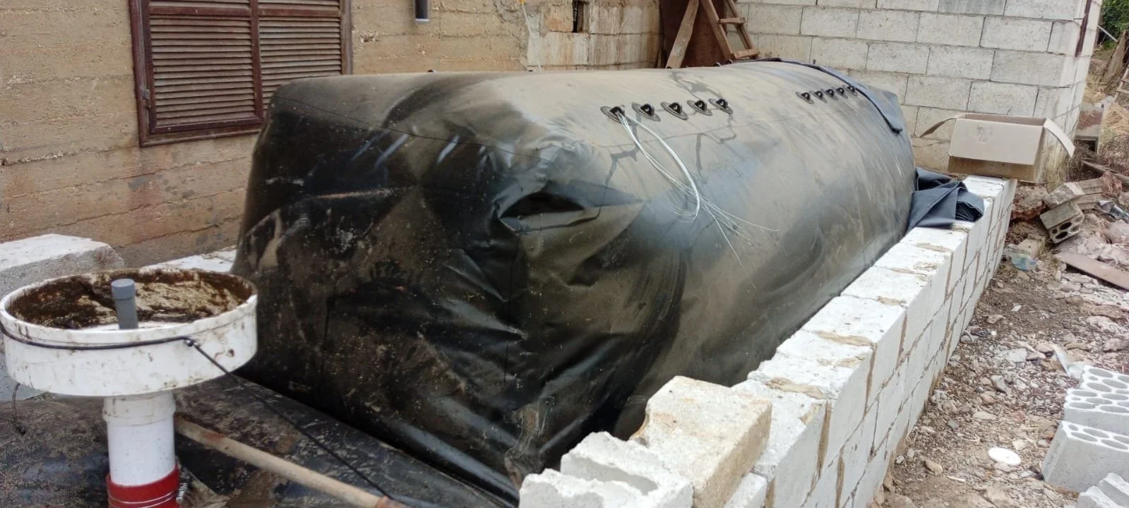 Indoor vermicompost pile with bags and tools nearby