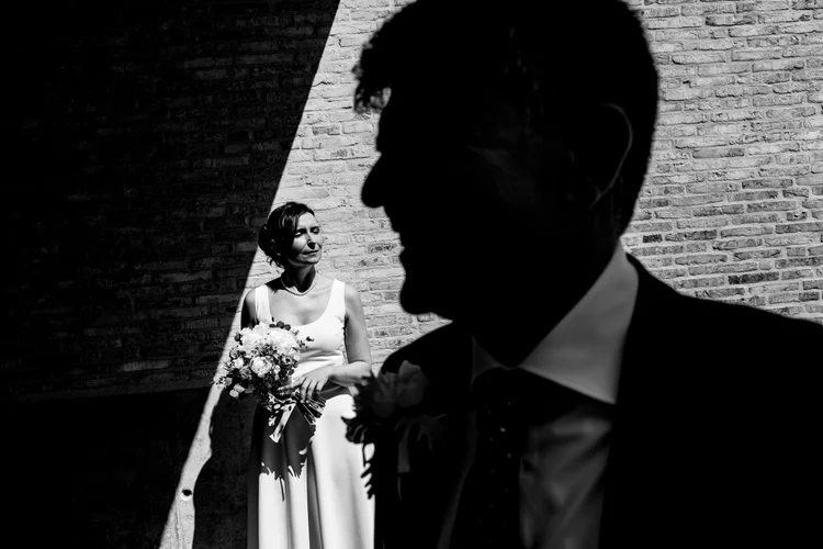 De bruidegom in silhouet met de bruid in het licht, in zwart-wit