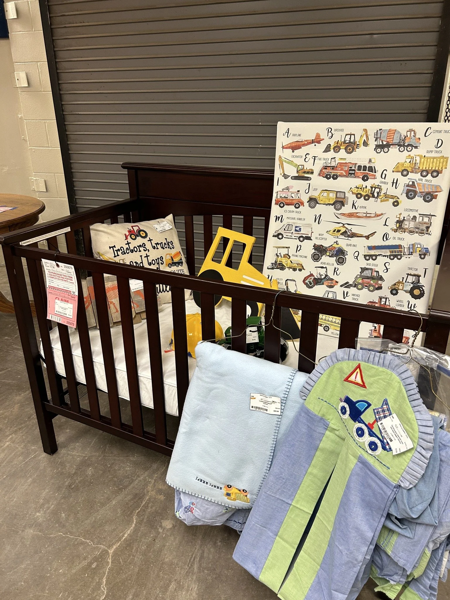 Display of children's bedding with machine embroidery, featuring tractor designs, in a store aisle.
