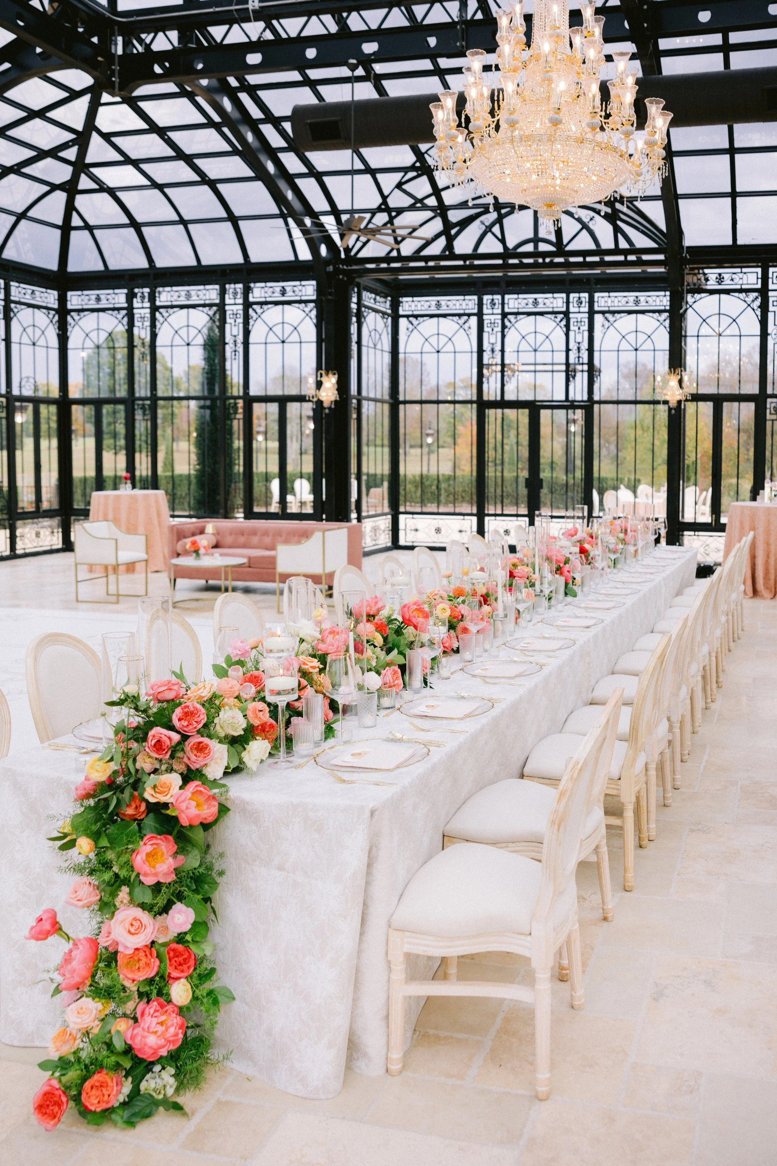 Elegant reception inside The Conservatory at Blackberry Ridge with glass architecture and long floral tablescape