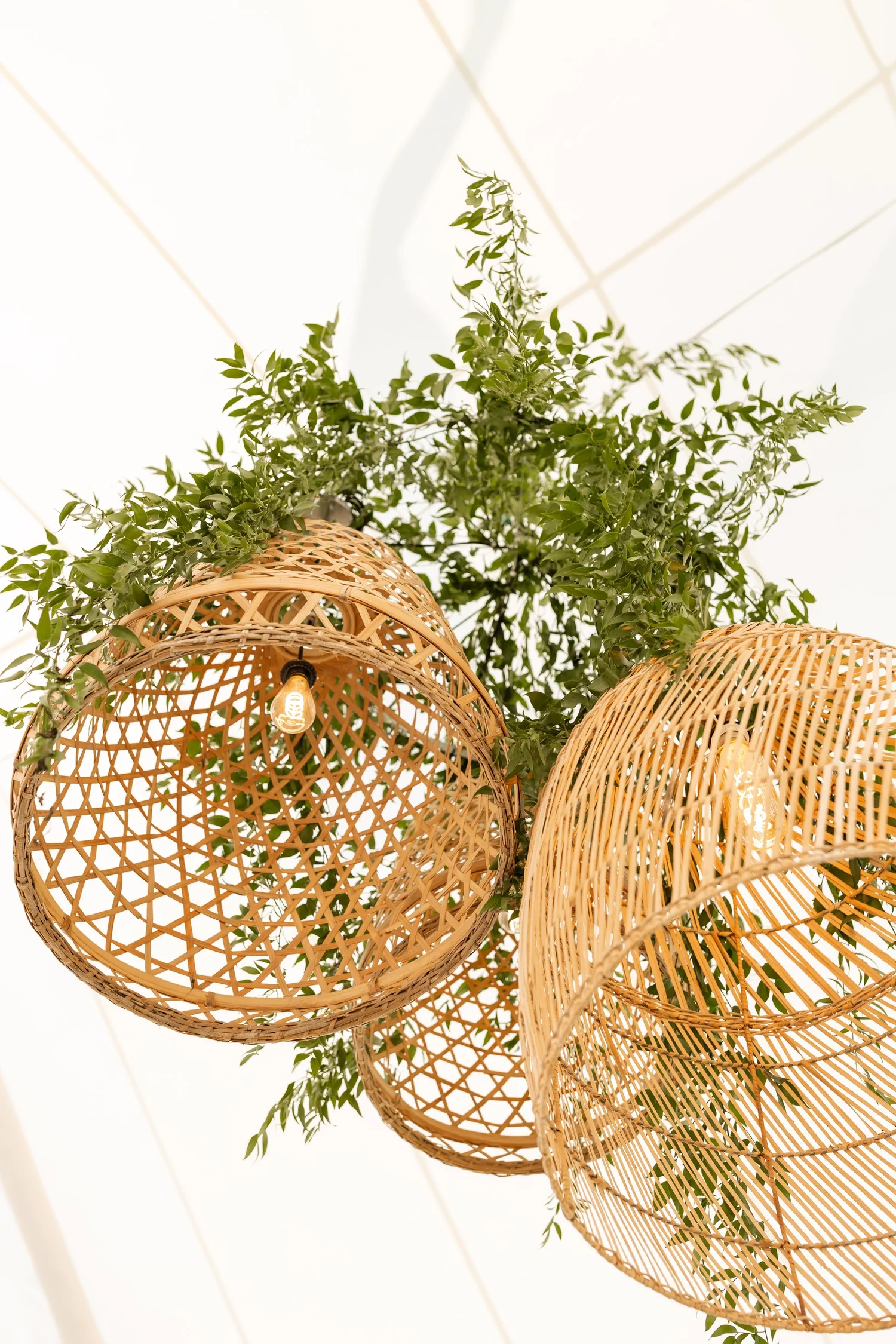 Close-up of clustered woven pendant light fixtures hung inside a sailcloth tent