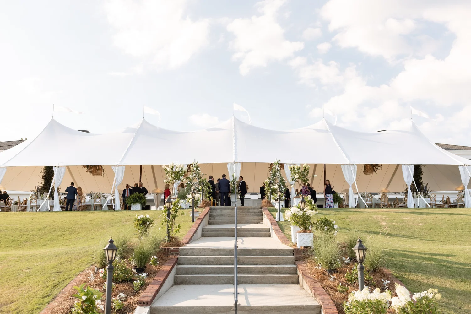Large white sailcloth wedding tent with draped openings and guest seating