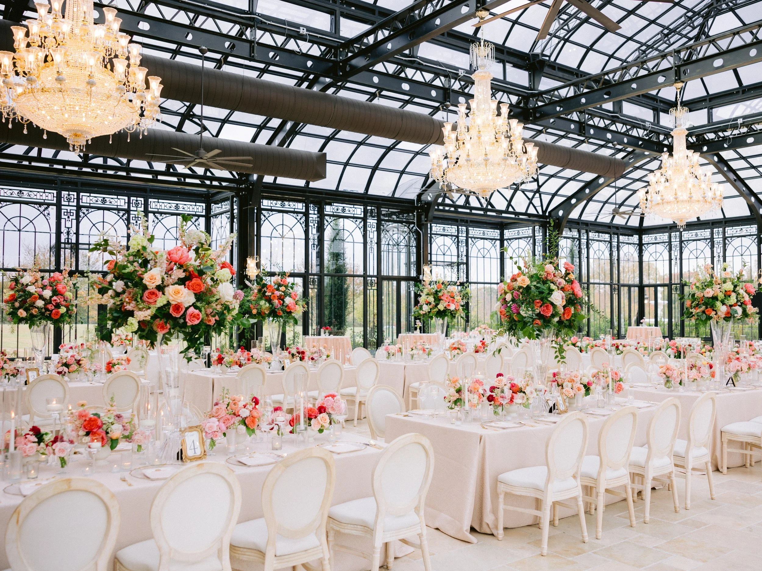 Glass conservatory with chandeliers and floral reception tables