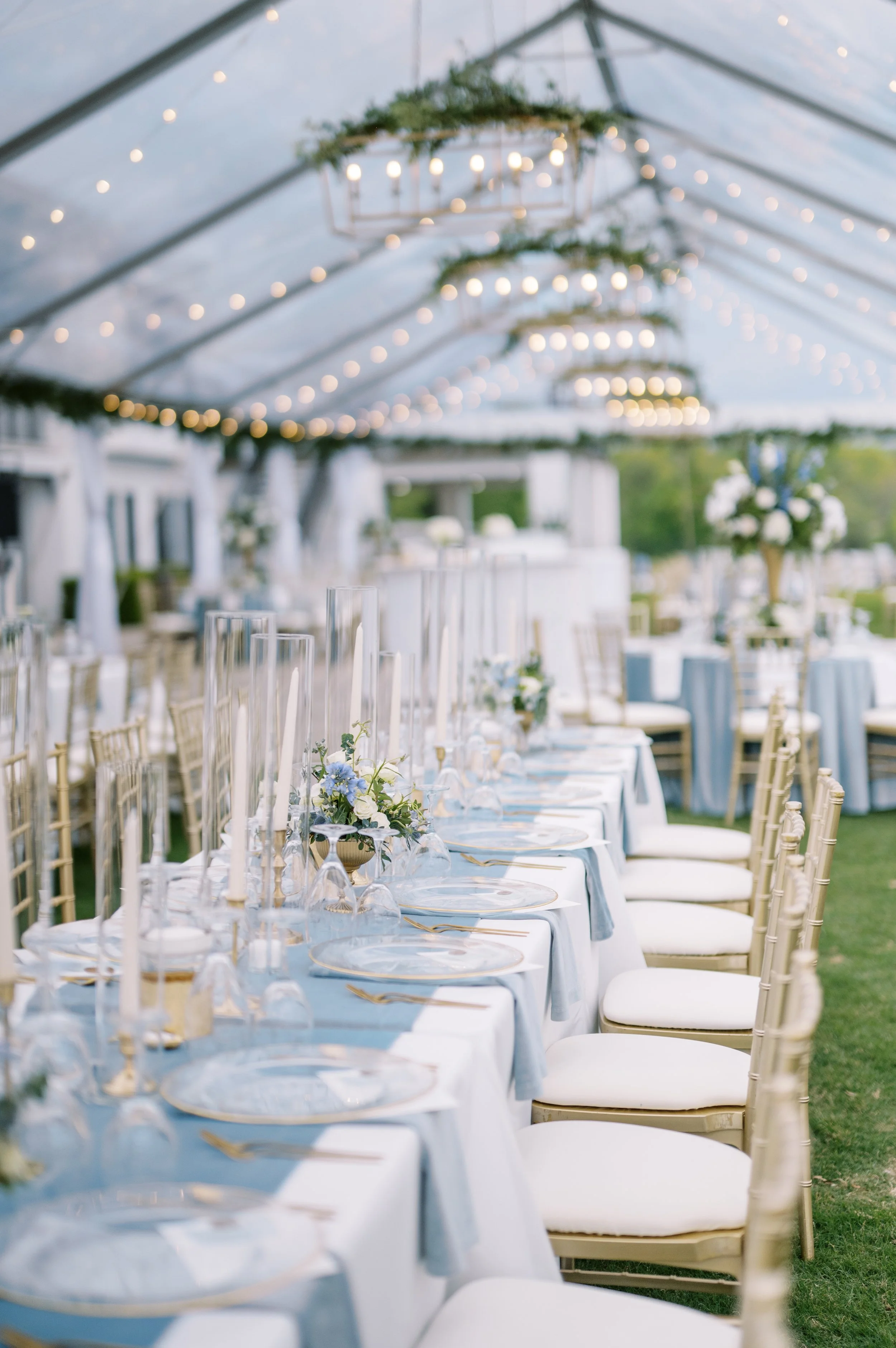 A long reception table beneath clear-top tent