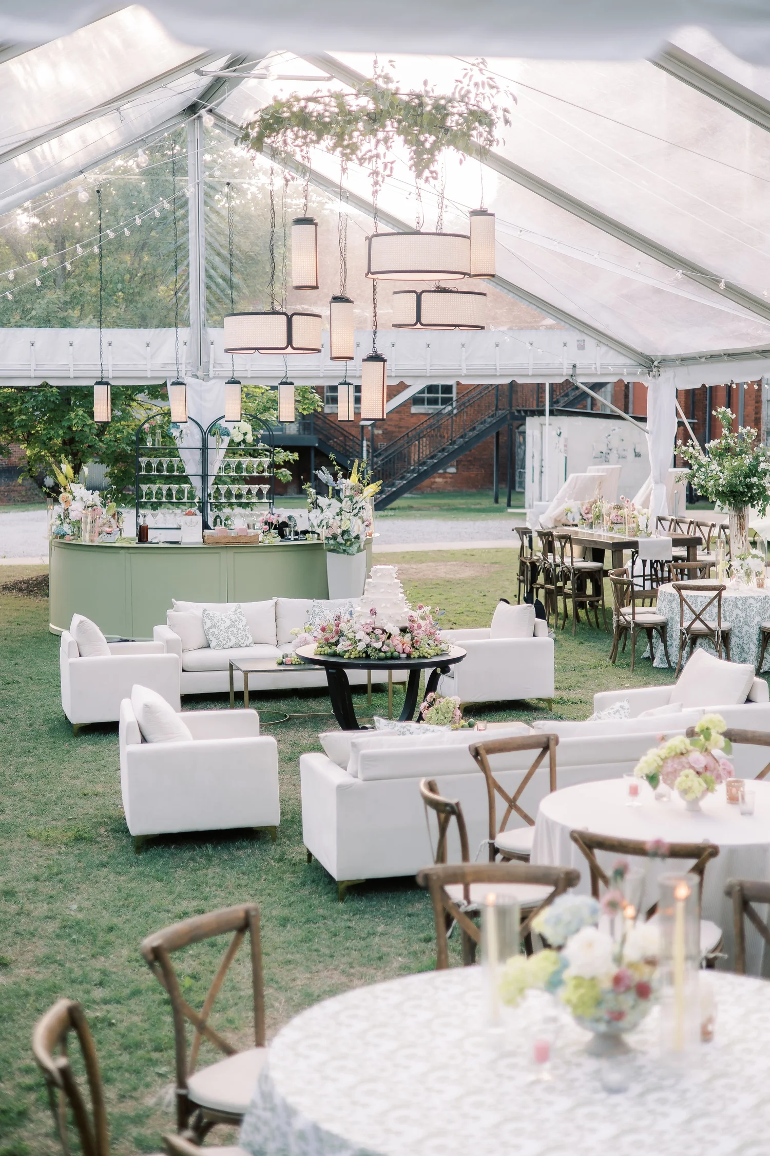 Fully styled event lounge and reception layout with sofas, cocktail seating and tables beneath a clear tent