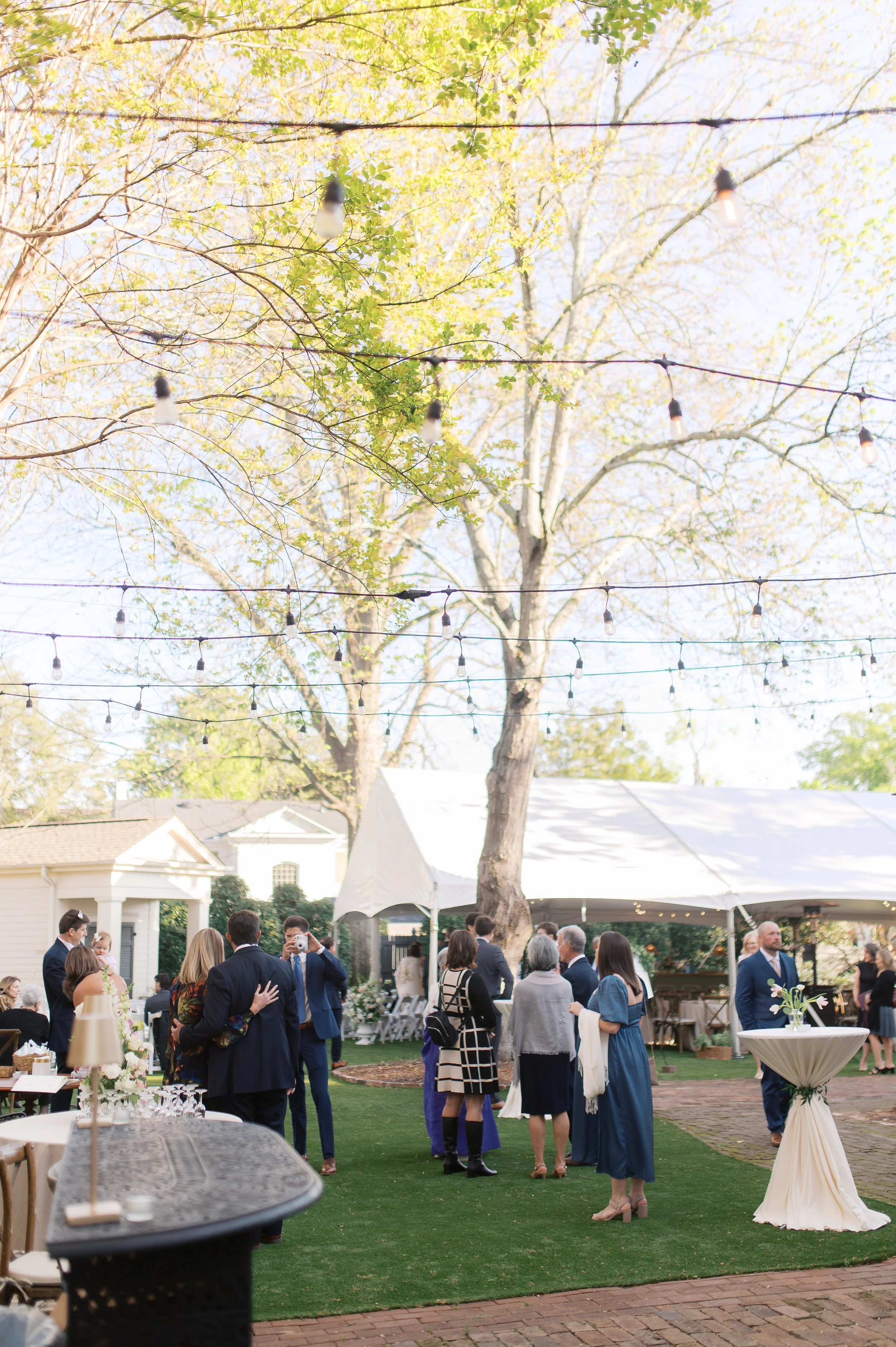 Garden reception with tent, string lights and cocktail tables