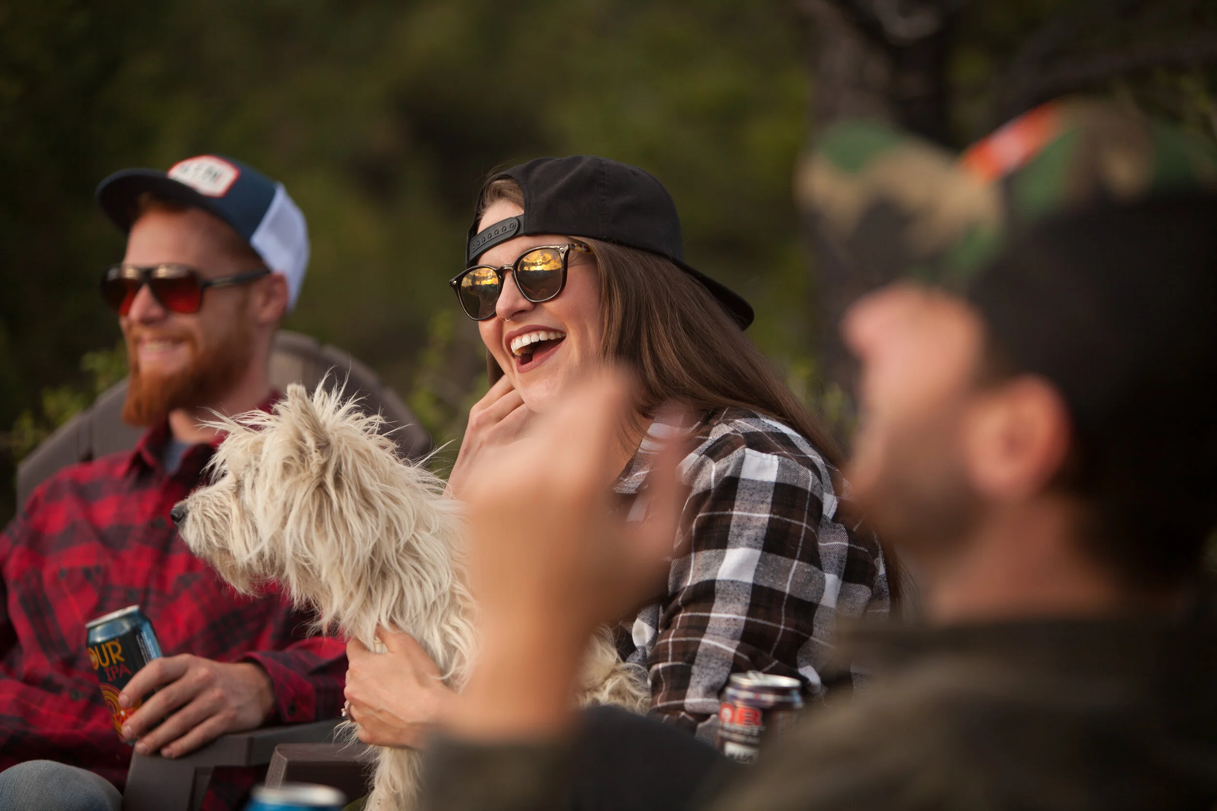 A girl and her dog enjoy a mountain sunset with cans of Epic Brewing beers.