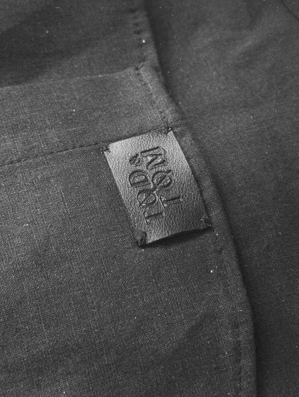 Close-up of a black fabric with a small leather tag that says 'LITE' in embossed letters.