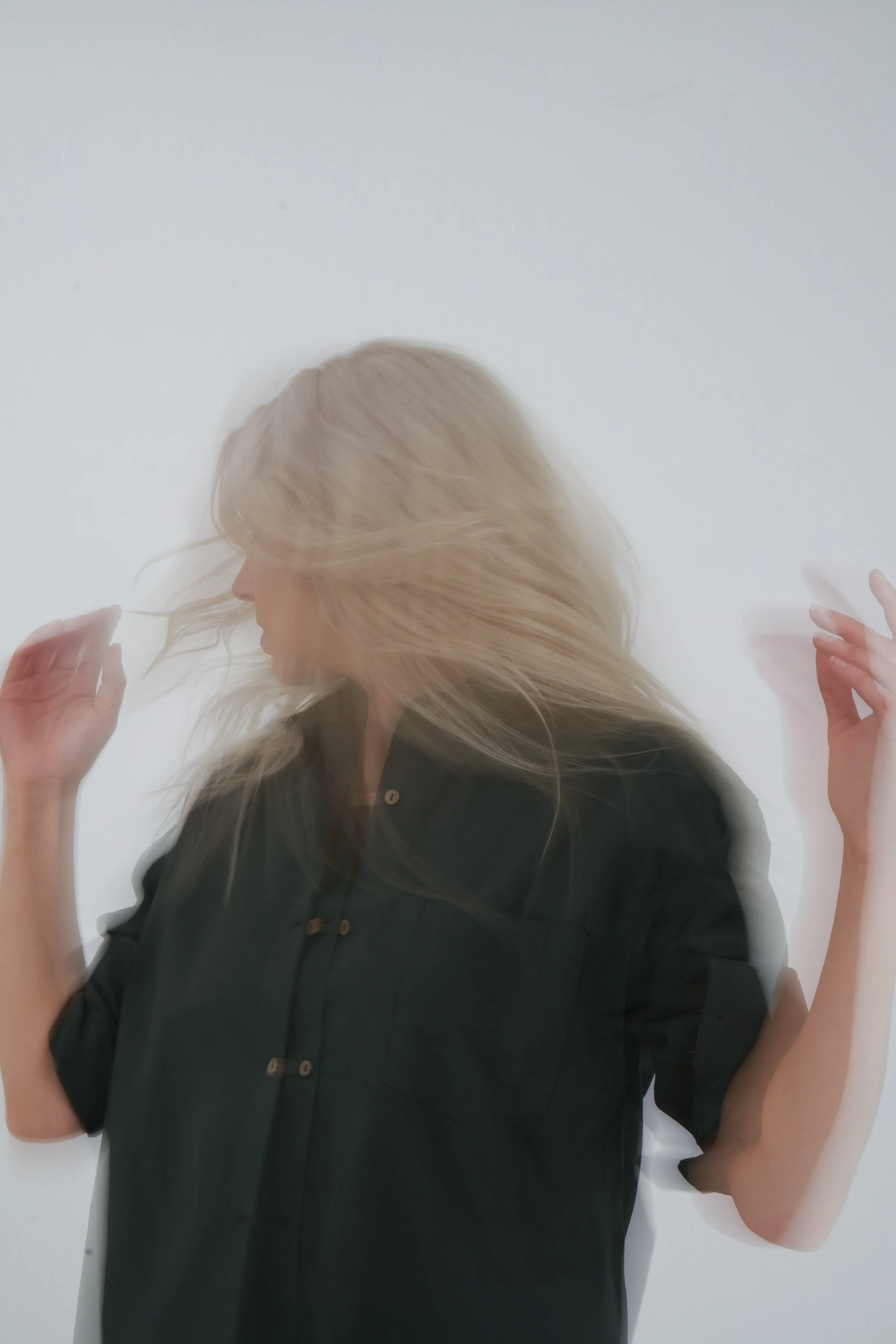 A woman with long blonde hair, wearing a black shirt, moving against a plain white background.