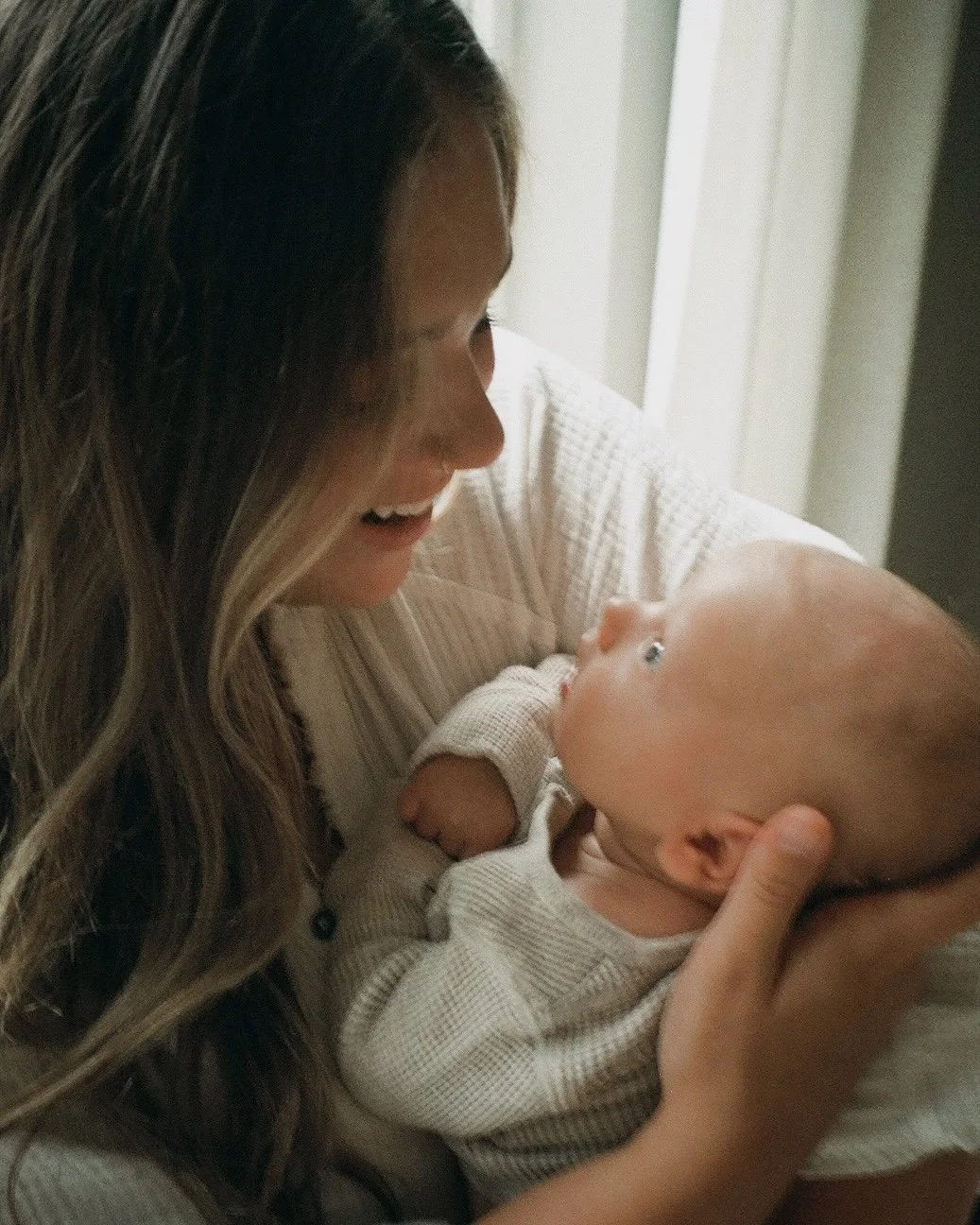 A woman holding a baby and smiling at each other.