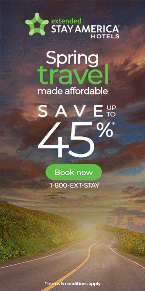 Advertisement for Stay America Hotels promoting spring travel discounts of up to 45%, with a scenic road and landscape background.
