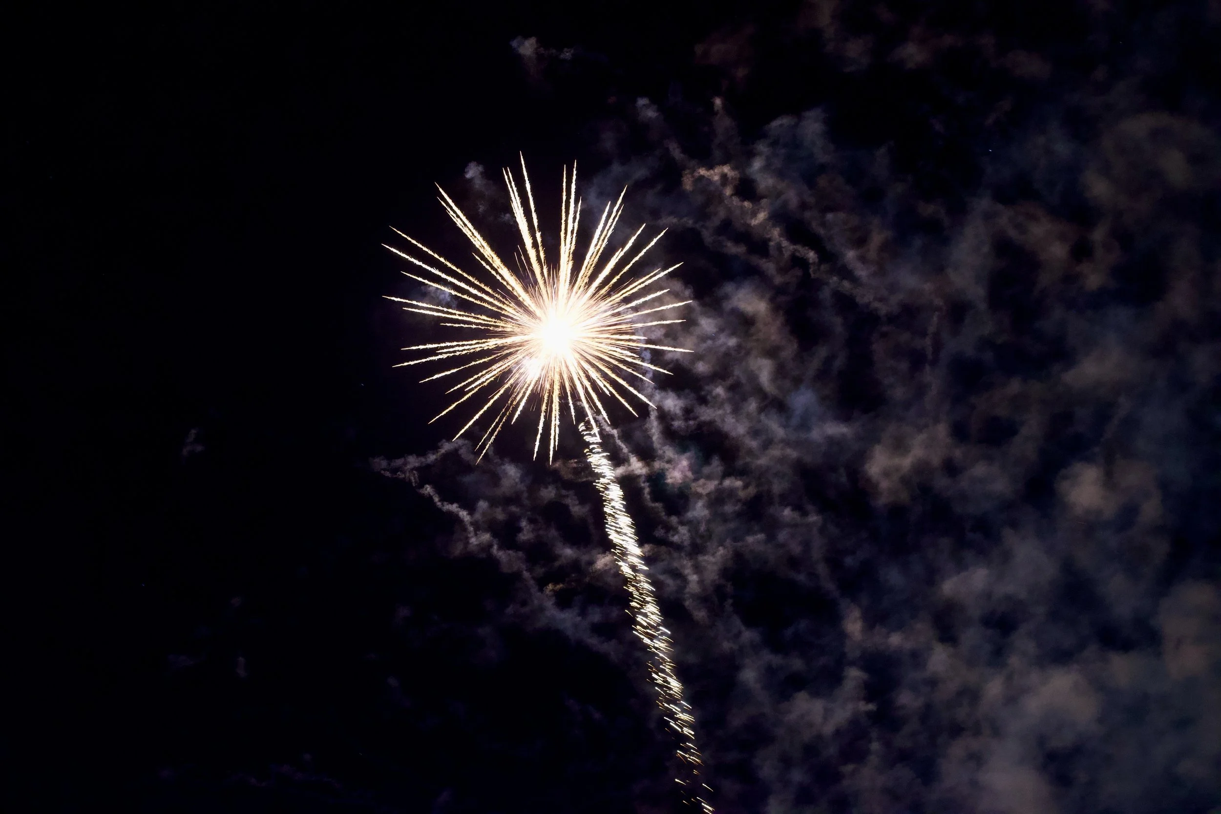 Fireworks exploding in the night sky with colorful smoke clouds around.