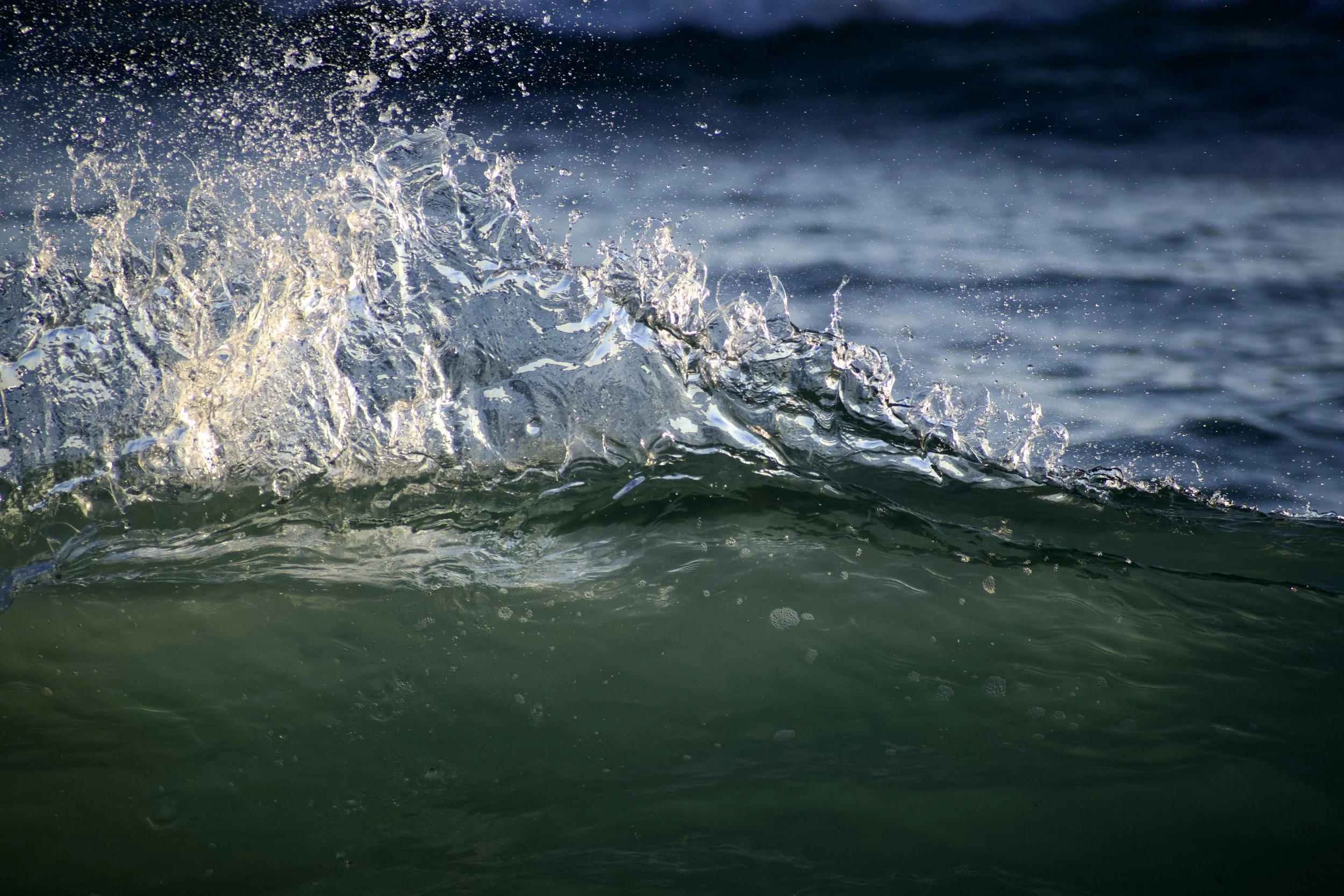 Close-up of ocean waves with water splashing and reflecting sunlight.