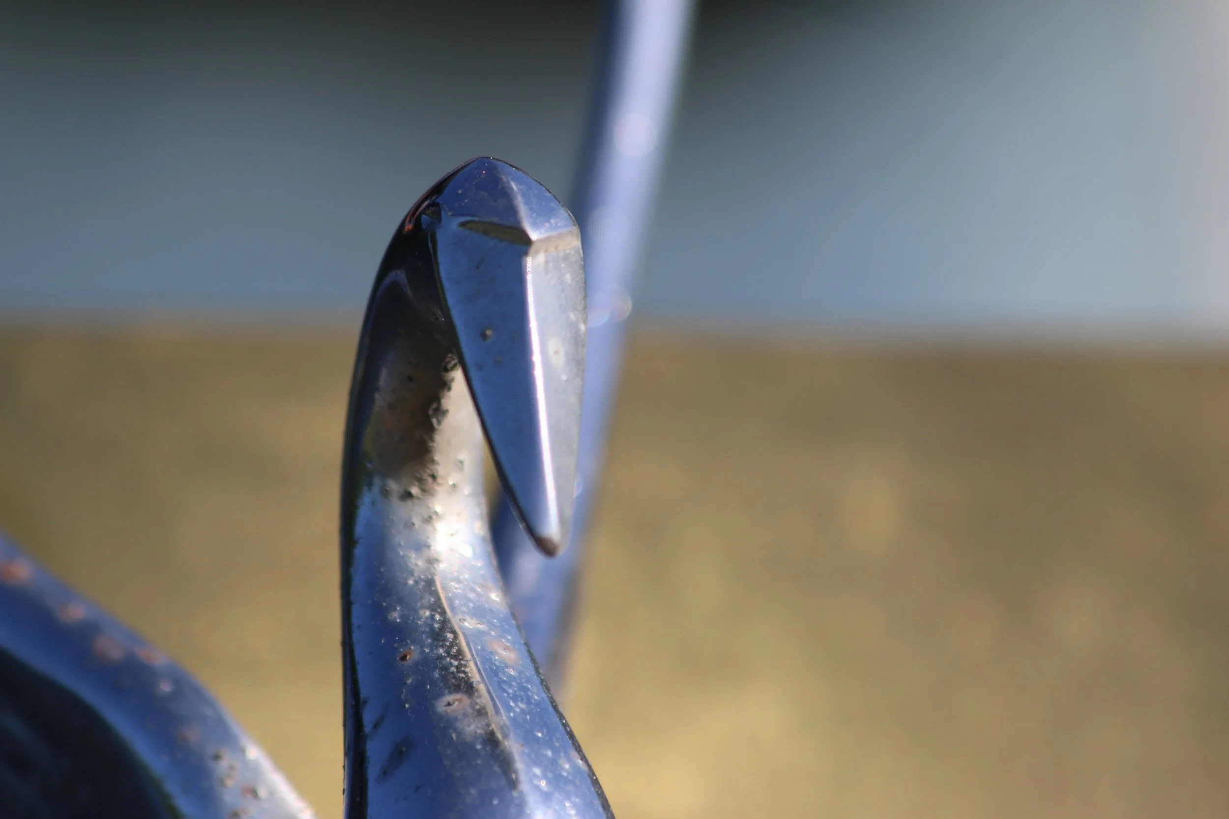 Close-up of a metal sculpture with swirling, curved shapes, on a blurred outdoor background.