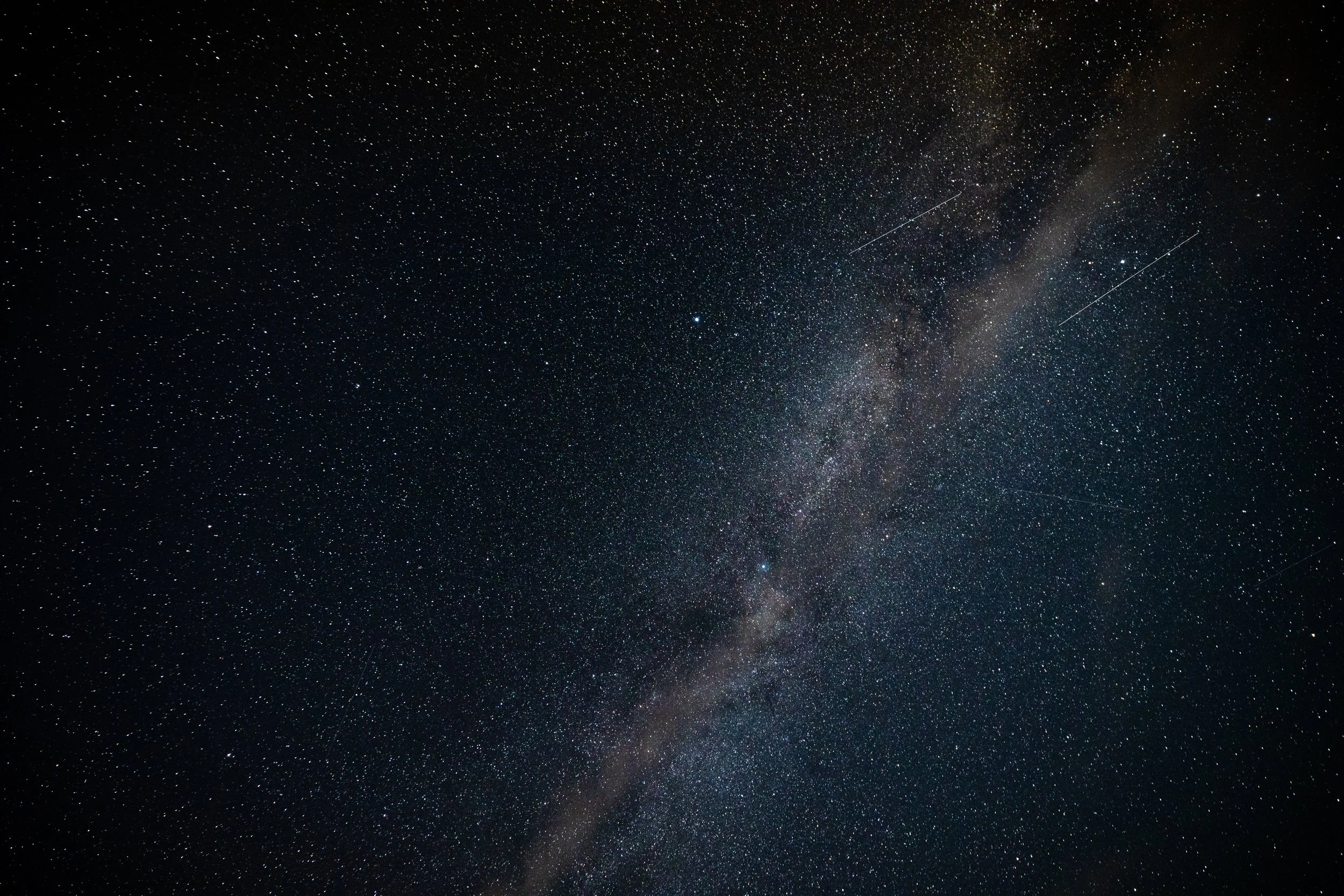 A clear night sky filled with numerous stars, with the Milky Way galaxy visible as a dense band of stars and cosmic dust stretching across the sky.