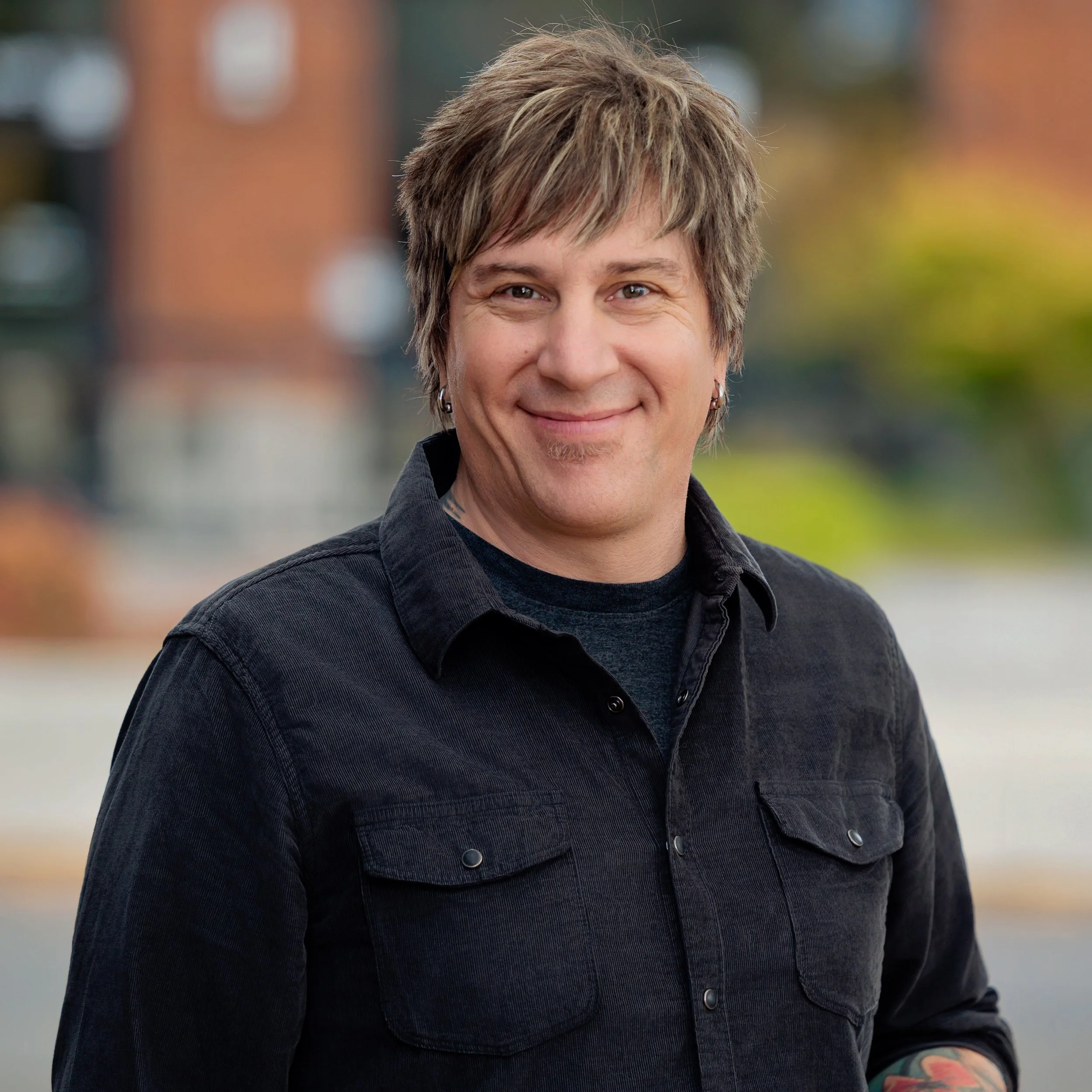 A picture of Matt Murray, who is a middle-aged white male with brown and blonde highlights, silver earrings a black corduroy shirtshirt