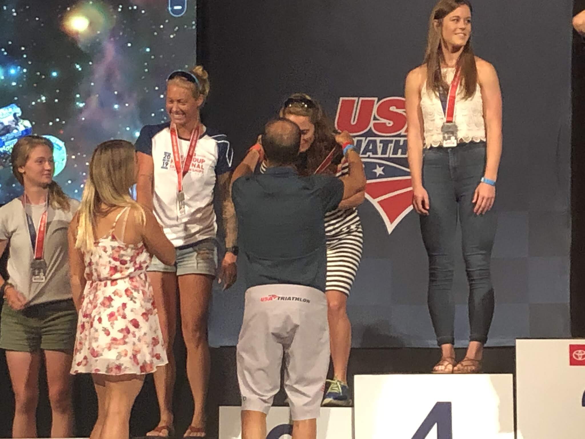People on a podium receiving awards at a USA Triathlon event.
