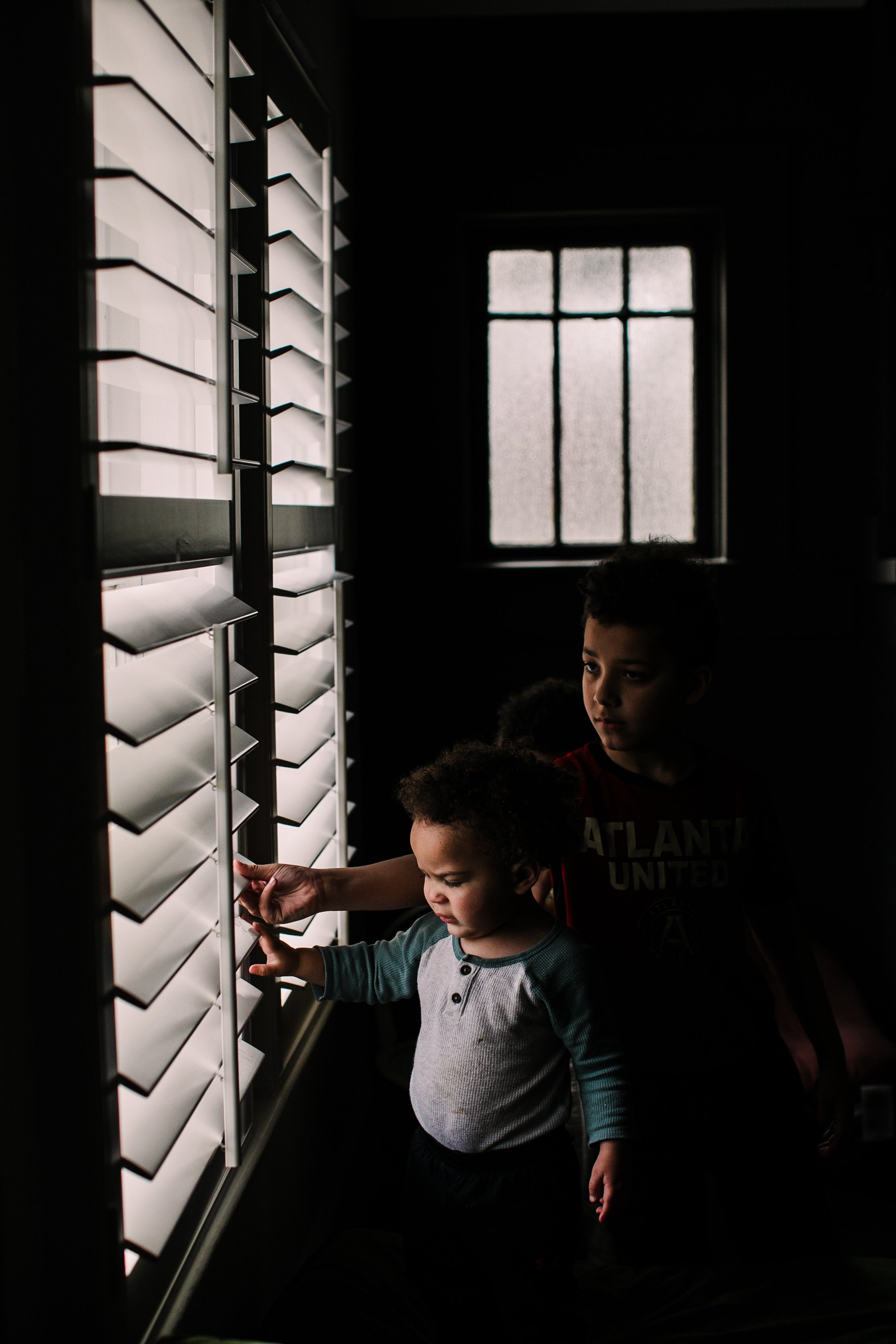 Atlanta in-home family photography session with kids peeking out the blinds of their home