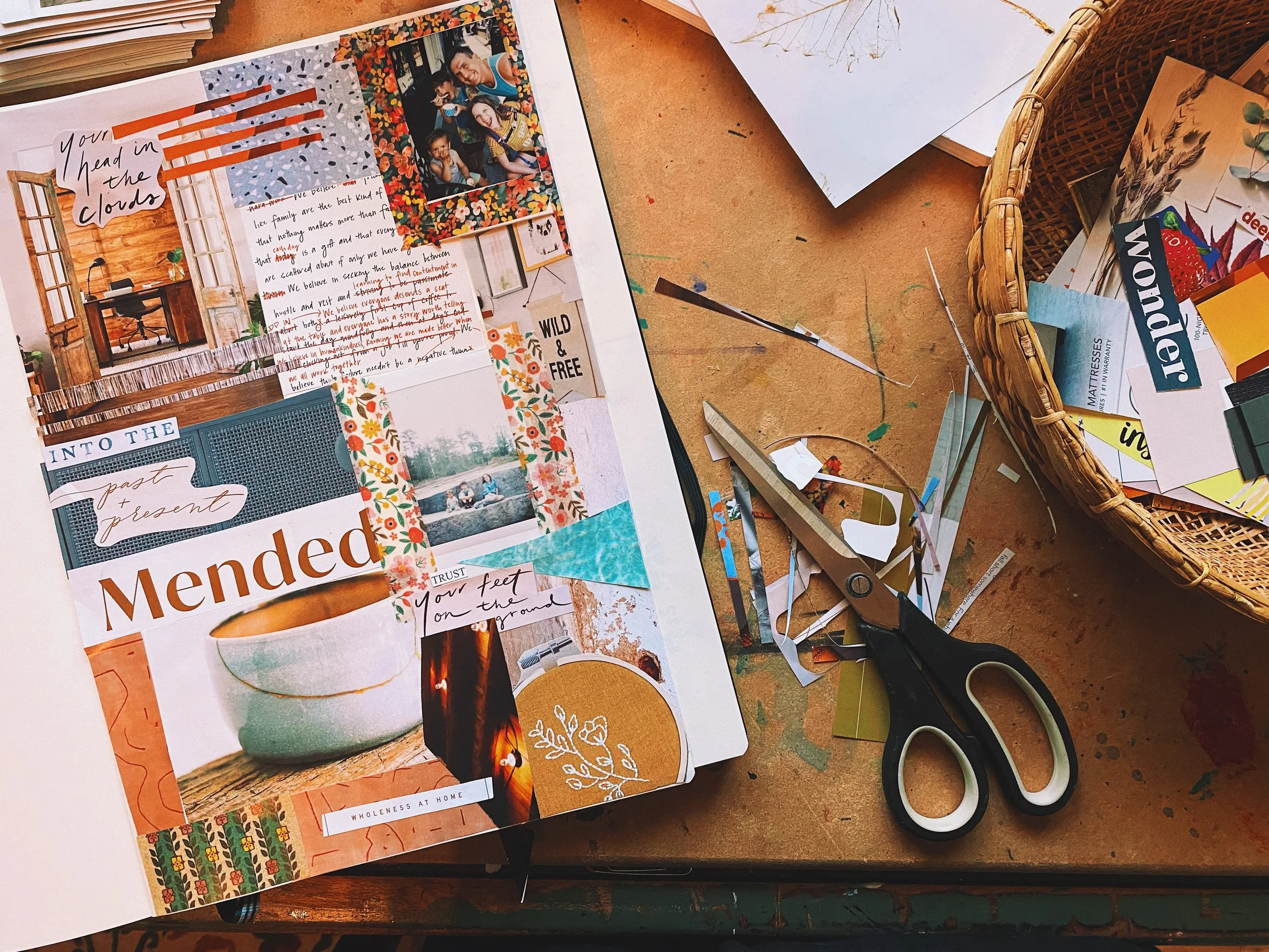 Atlanta lifestyle photographer captures image of a worktable with a collage of scrapbook paper, photos, and decorative elements, along with scissors, used for arts and crafts projects.