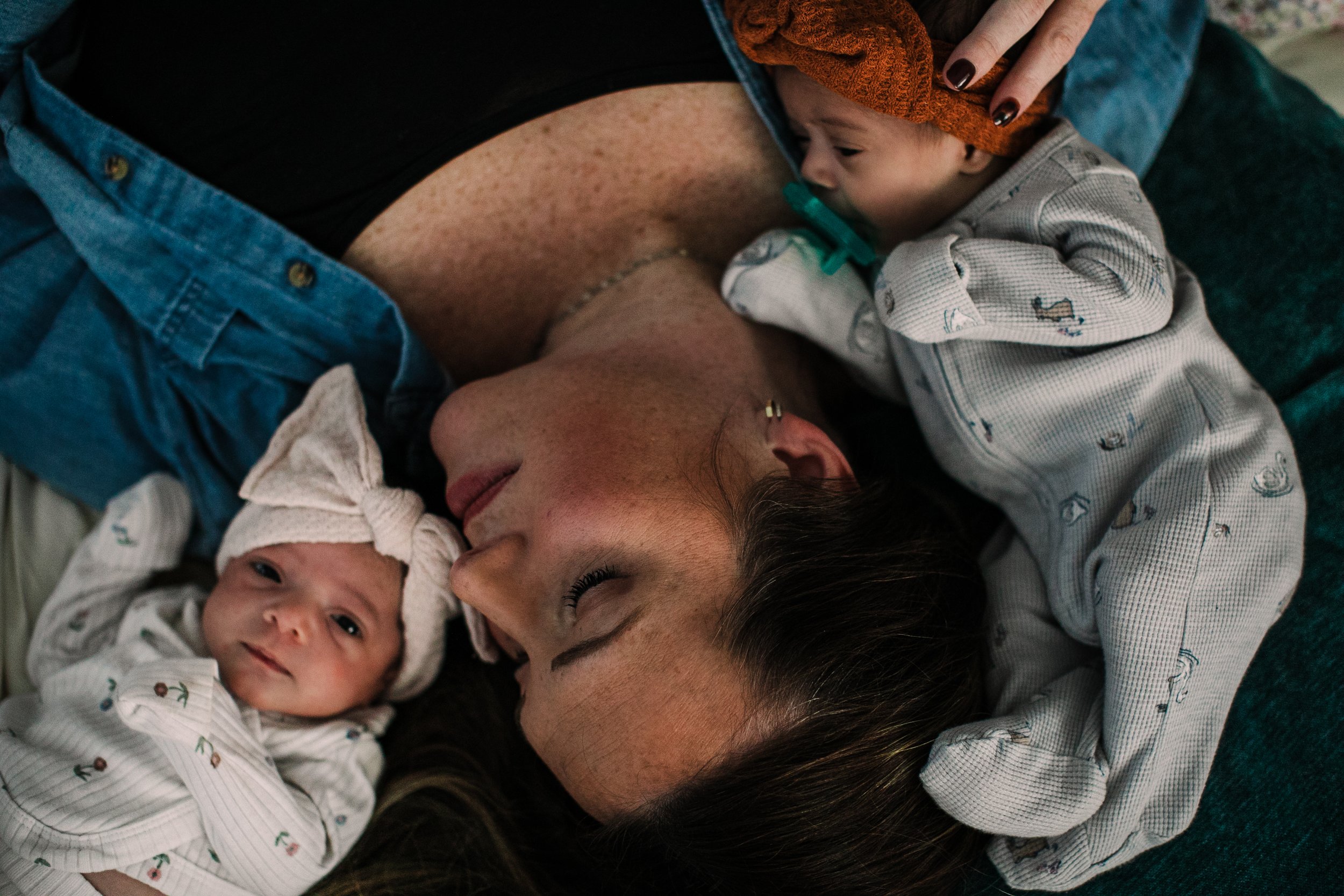 Atlanta documentary in-home newborn photographer shows mother laying down next to her twin newborn babies.