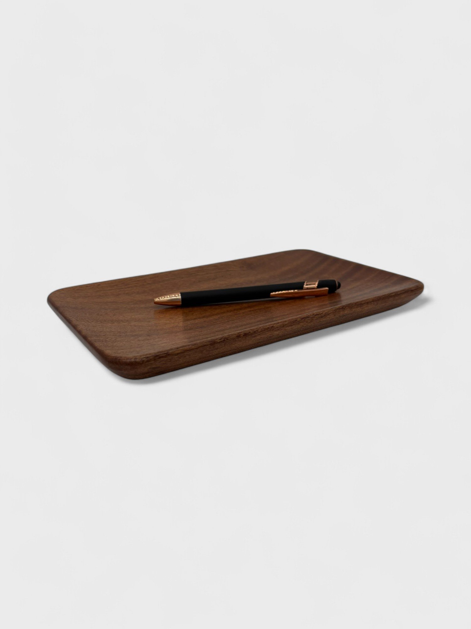 a small tray made from Sepele wood with a pen on it
