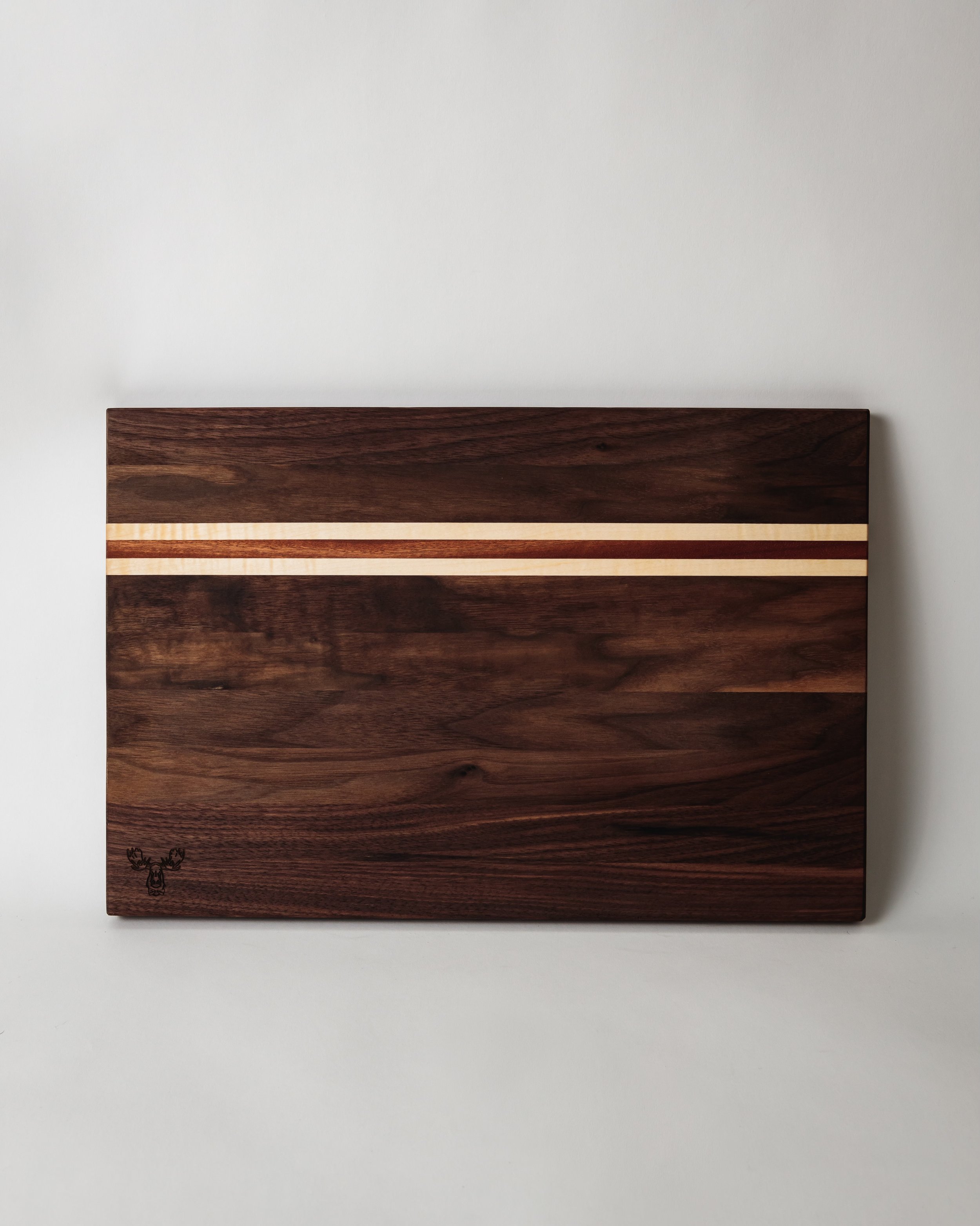 a cutting board with stripes of wood made from walnut, maple, and bloodwood
