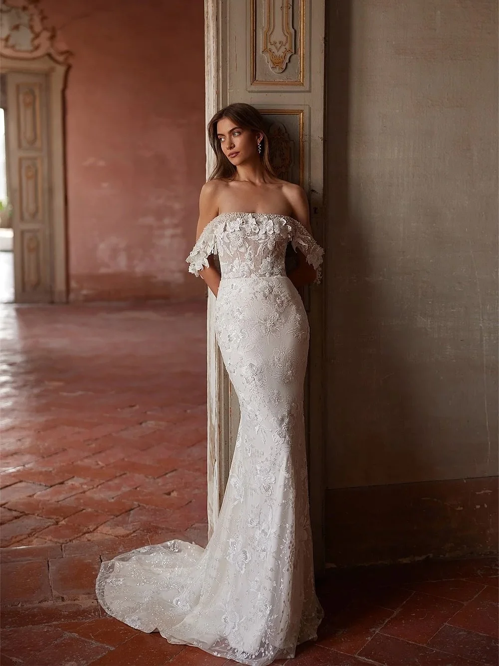A vision of romance.
This off-the-shoulder gown stuns with 3D floral appliqu&eacute;, a sheer corset bodice, and a detachable overskirt for two unforgettable looks in one. Perfect for the bride who wants elegance with a touch of modern allure.

#bgsb