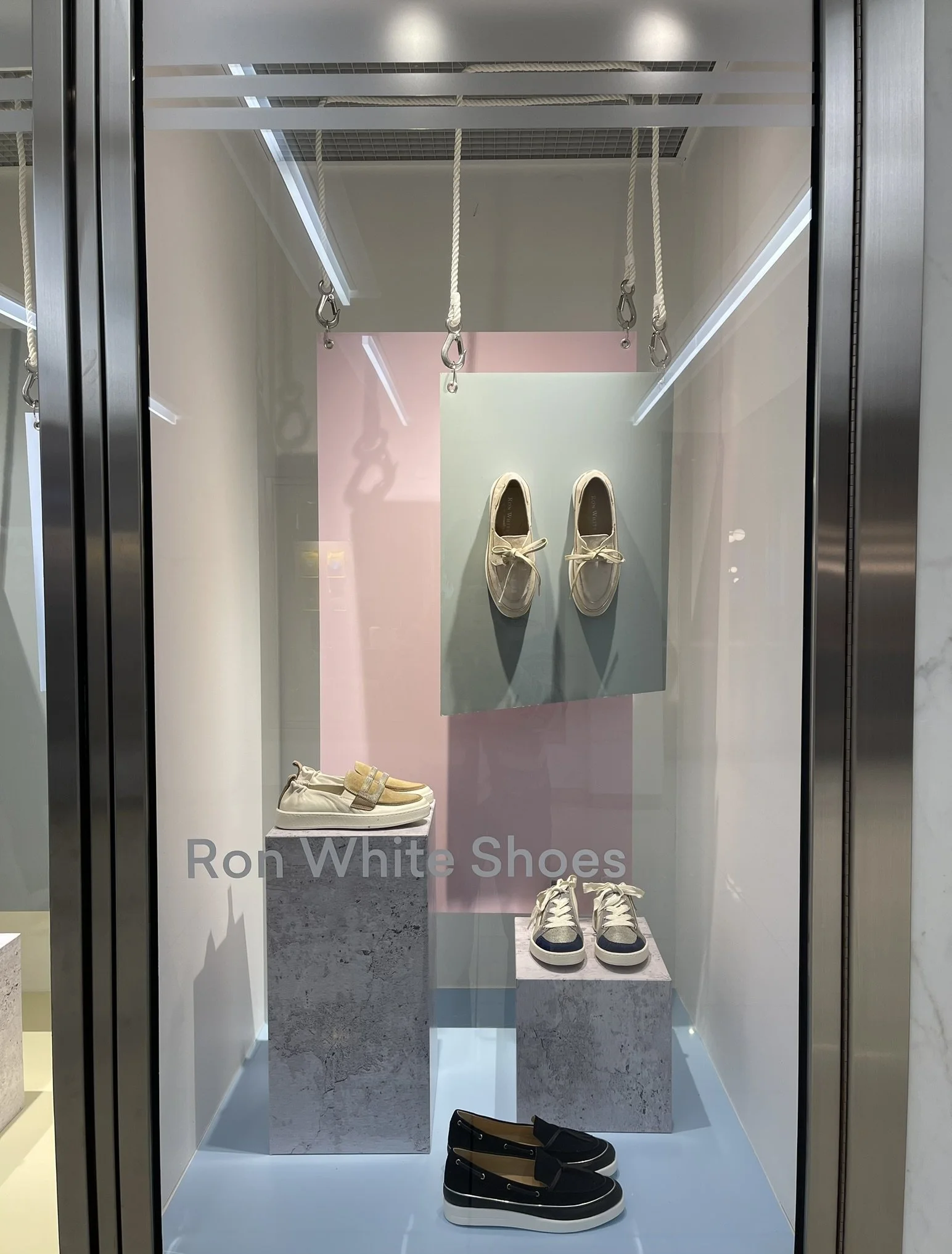 Custom window display for Ron White Shoes at Manulife Centre, showcasing footwear through a cohesive multi-brand visual merchandising program designed for shopping centre tenants.