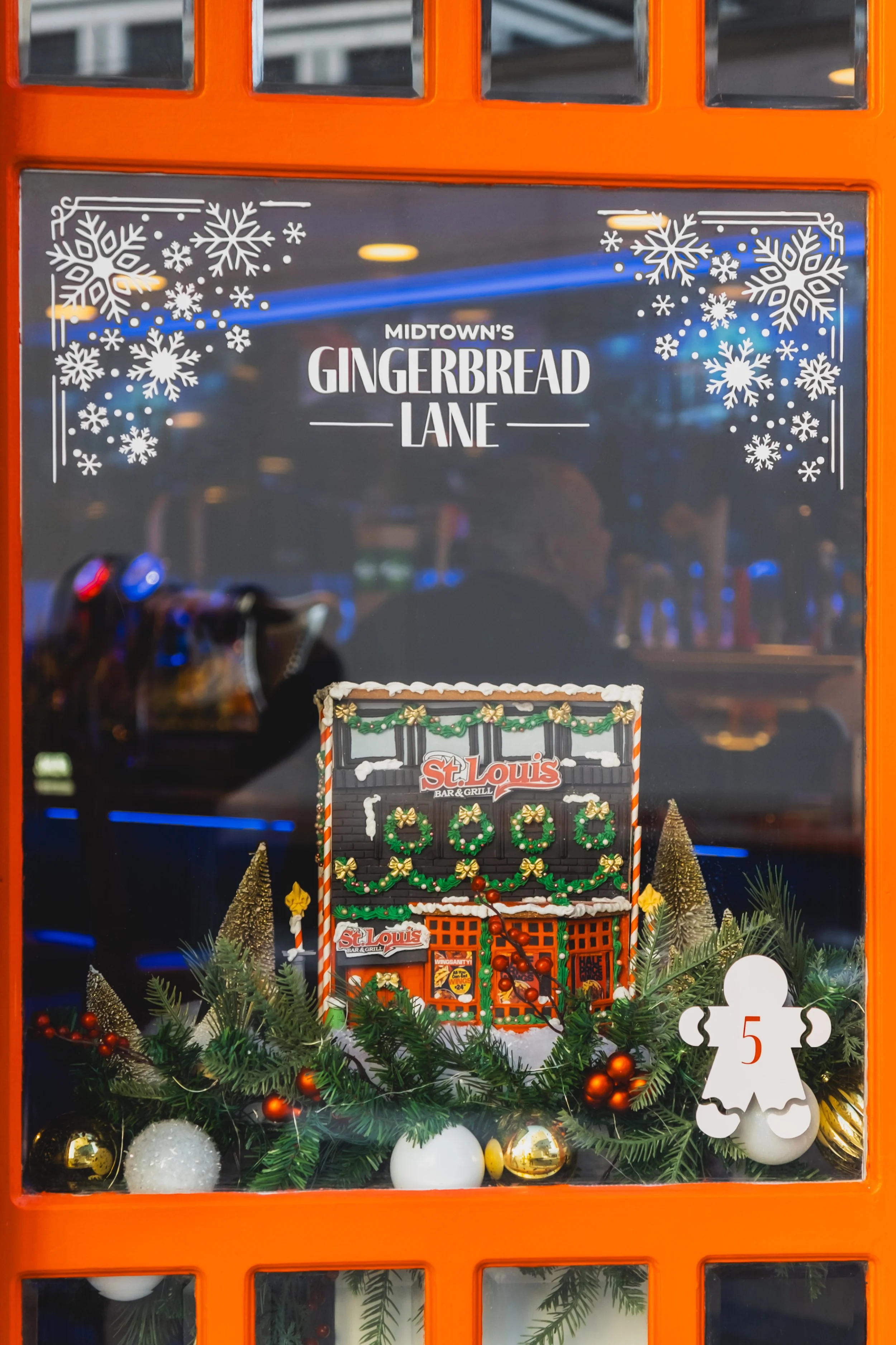 Holiday salon window display featuring a gingerbread house centerpiece framed by festive garland for Midtown’s Gingerbread Lane in Toronto.