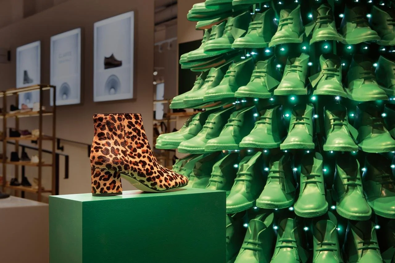 Clarks holiday window display featuring a Christmas tree made from repeated green shoe forms.