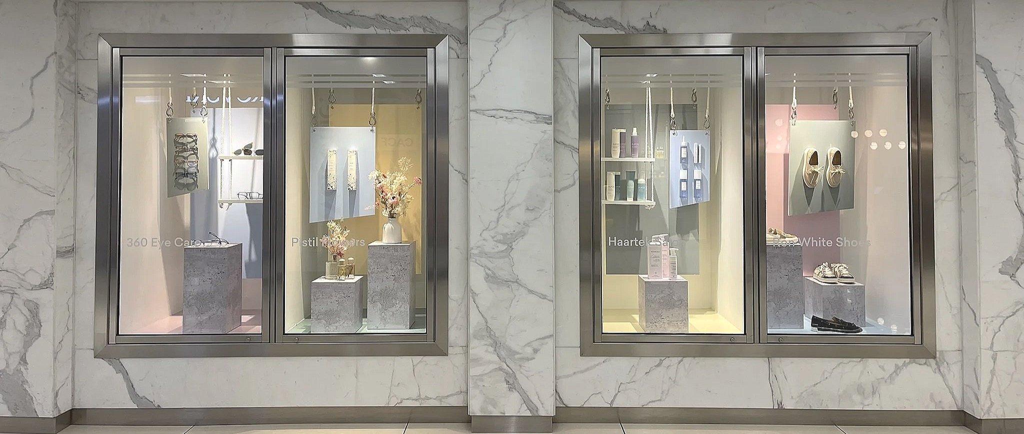 Wide view of a multi-brand window display series at Manulife Shopping Centre, by Yorkville, designed to showcase multiple tenants through a cohesive visual merchandising program for property-led retail environments.