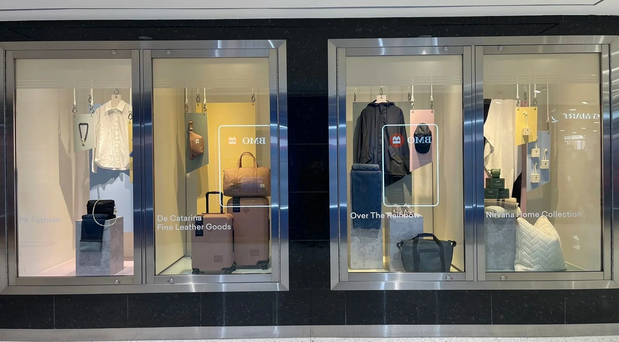 Fashion and accessories window displays for PK Fashion and De Catarina Fine Leather Goods at Manulife Centre, styled as part of a coordinated multi-brand visual merchandising initiative.