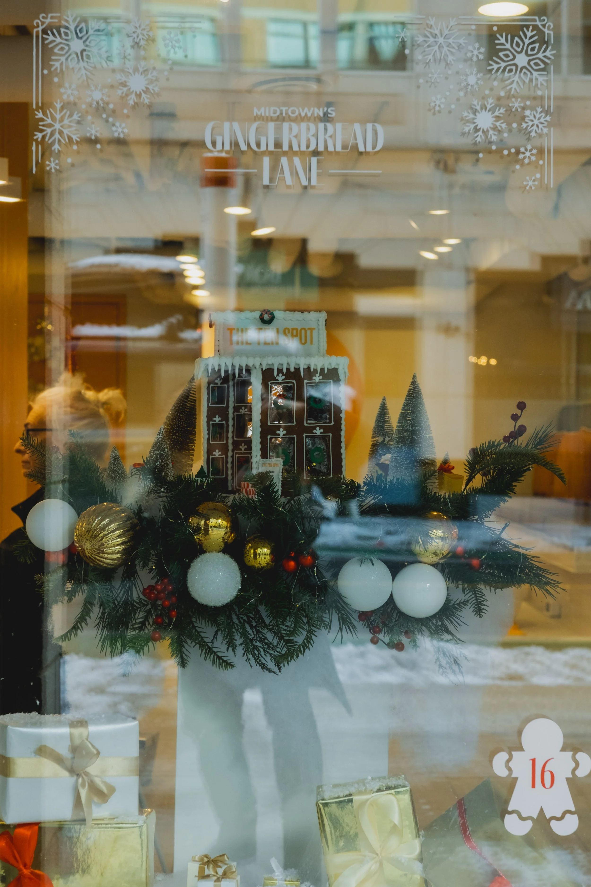 Holiday bar window display featuring a gingerbread building and festive greenery for Midtown’s Gingerbread Lane at Yonge St. Clair.