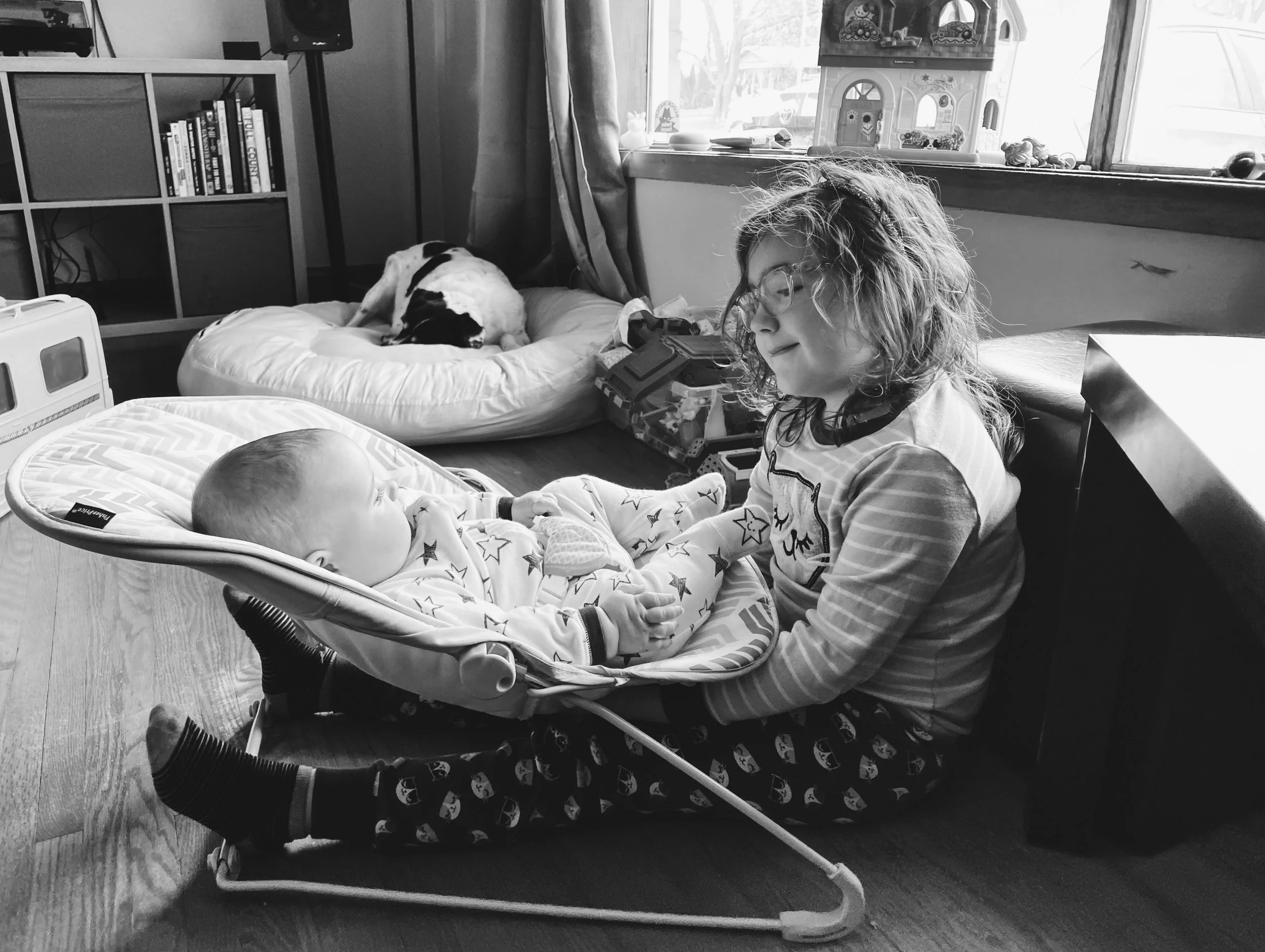 Big sister stares at little sister with tired dog in the background