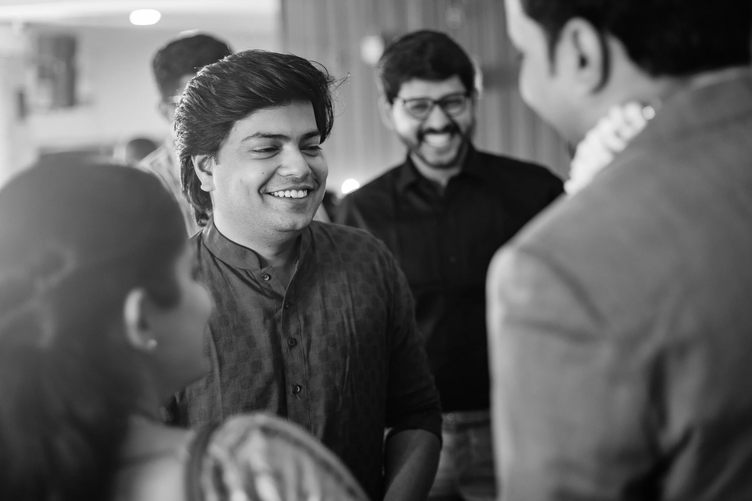 Group of people smiling and talking at a social gathering, black and white photo.