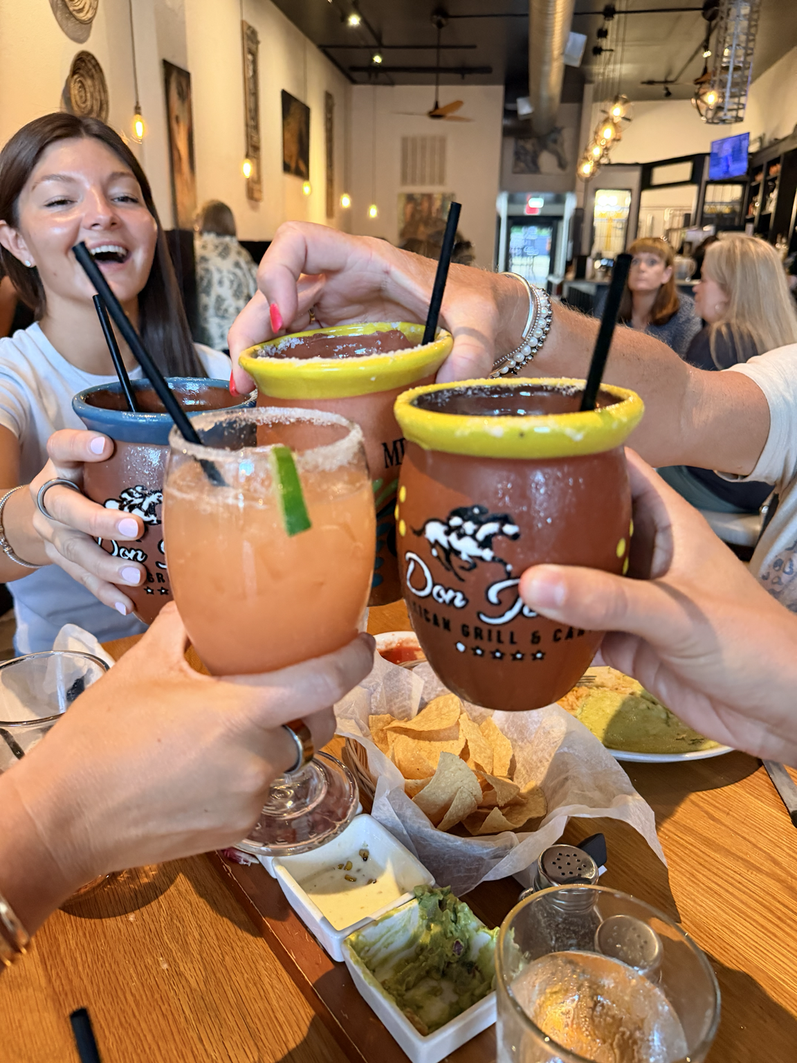 Friends enjoying Don Jockey Margaritas in signature clay cups at Don Jockey Mexican Grill & Cantina.