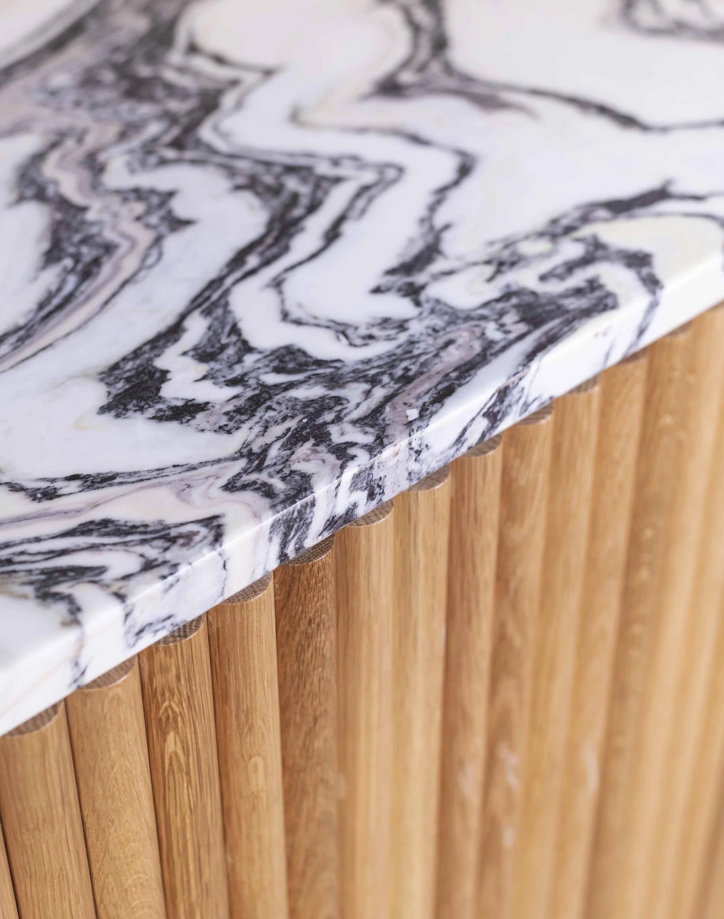 Close-up of a marble countertop with black and white swirled pattern, supported by wooden vertical slats.