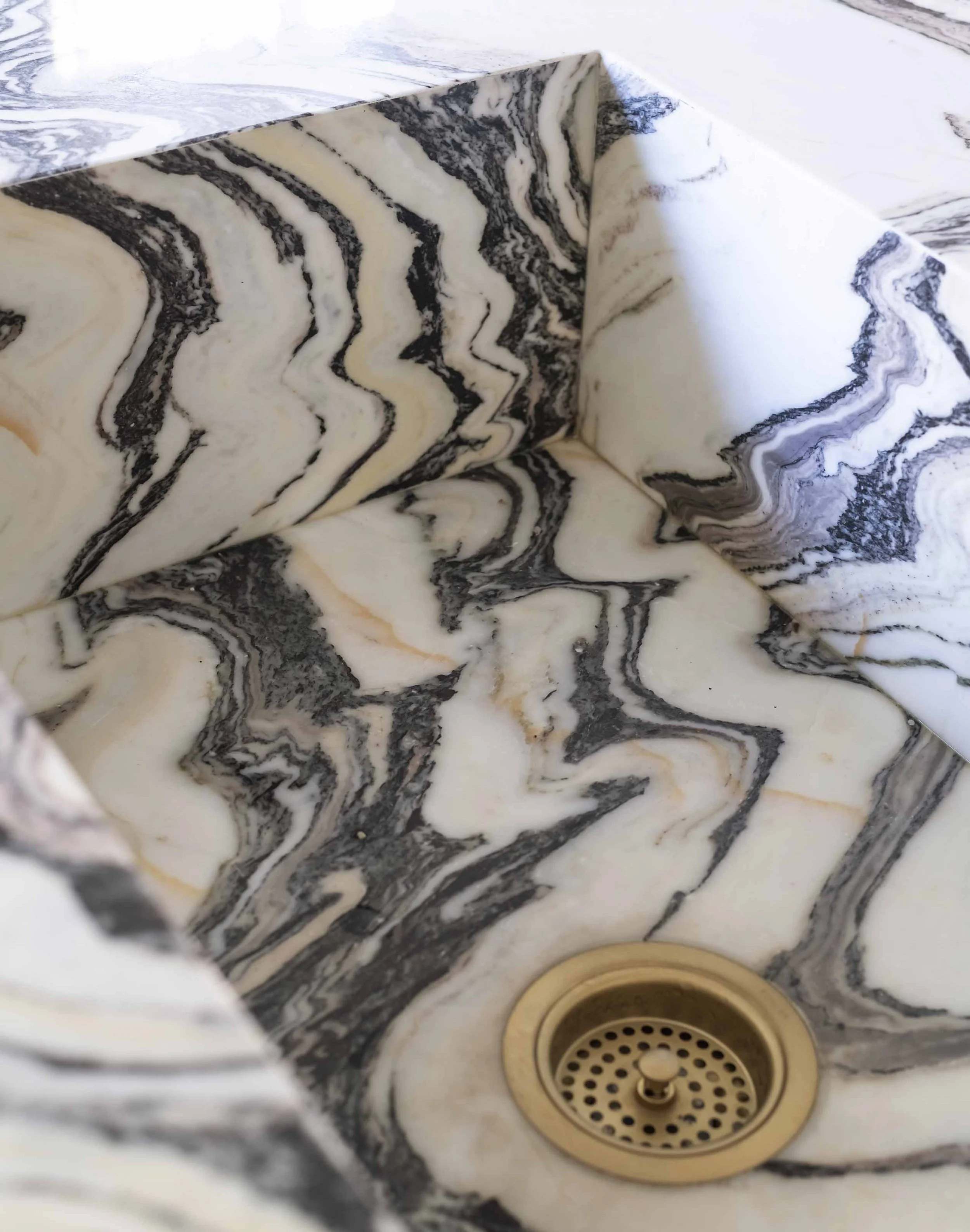 Marble-patterned kitchen sink with a gold-colored drain.