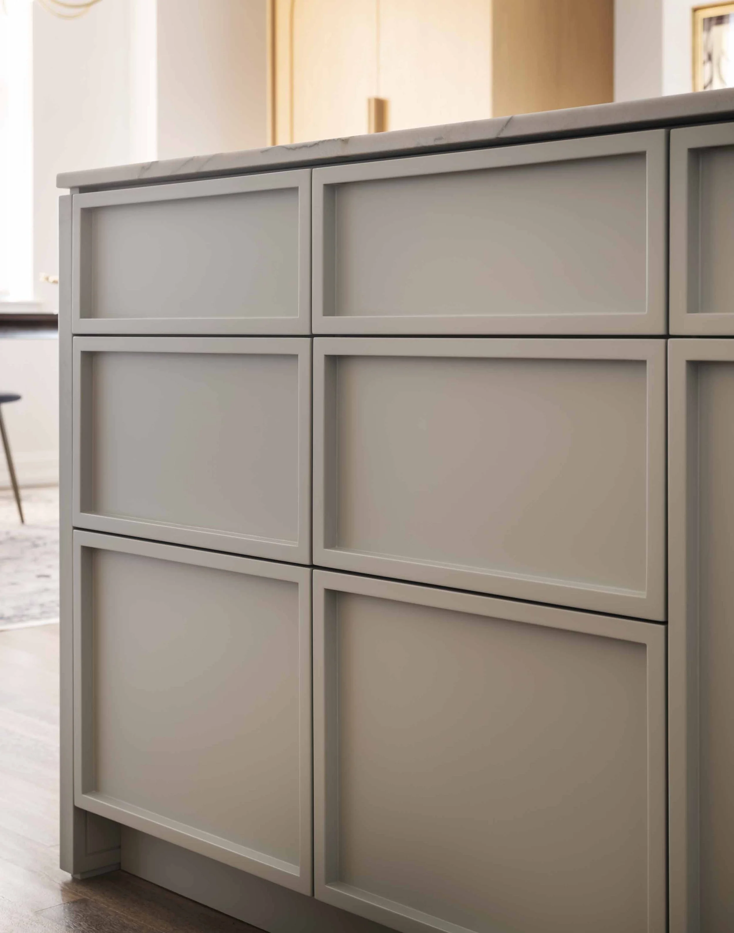 Close-up of a modern white cabinet with four drawers and a marble top, placed in a well-lit room.